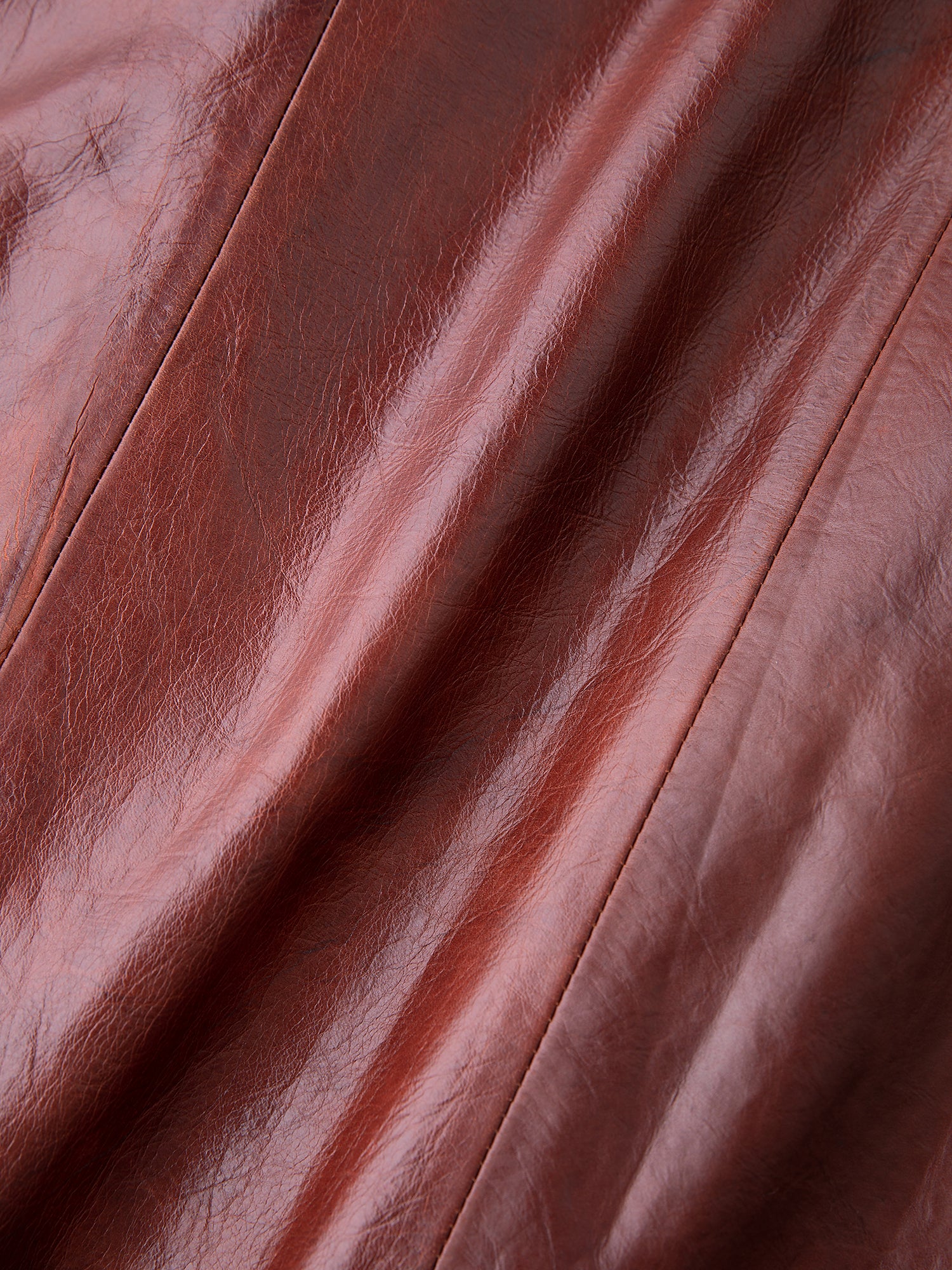 Close-up of brown leather texture with visible seams, smooth shiny surface, and natural creases typical of FOUND's Claret Western Oversized Leather Blazer, ideal for any unisex wardrobe.