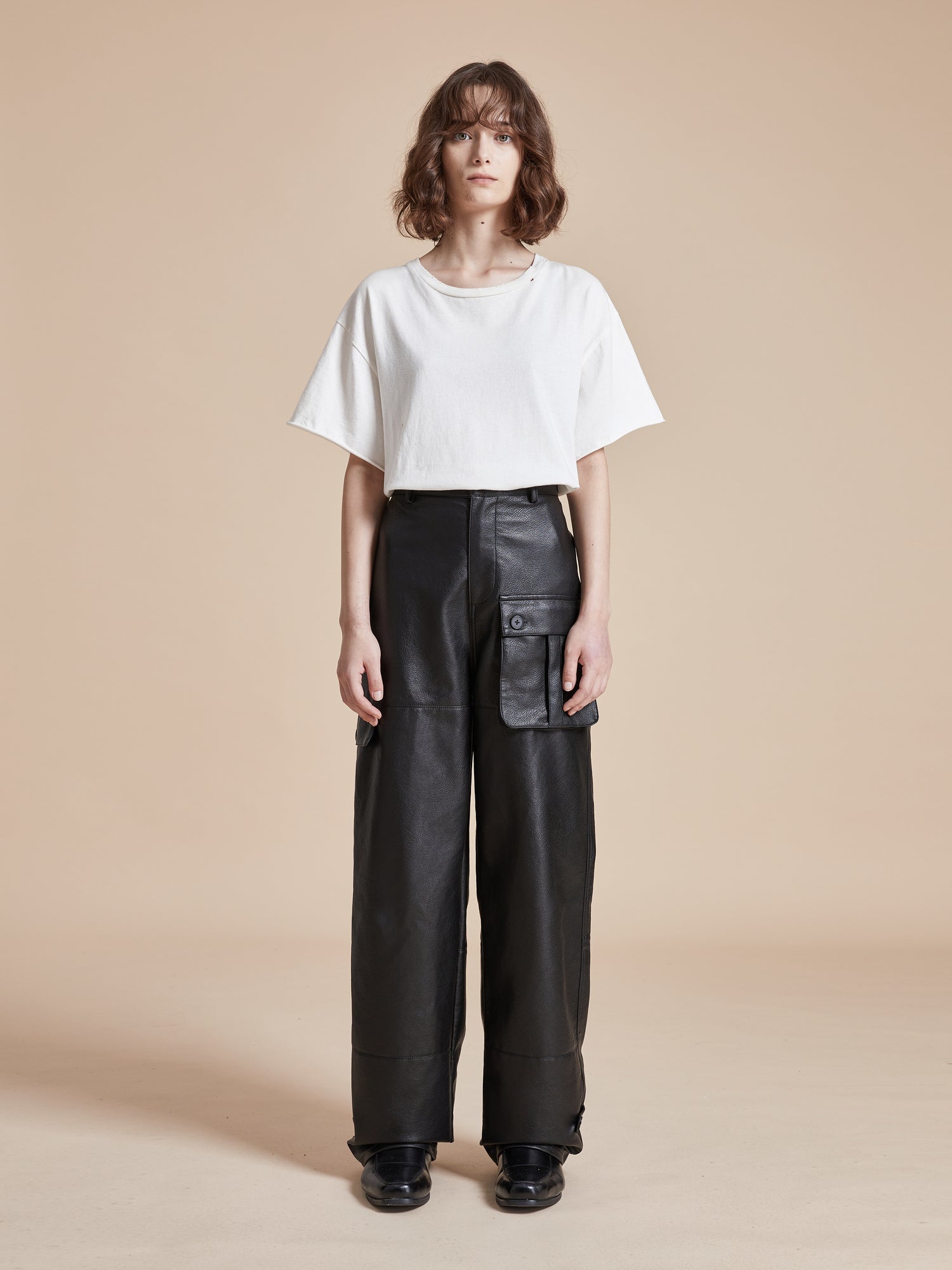 A model wearing Found Faux Leather Cargo Pants and a white t-shirt.