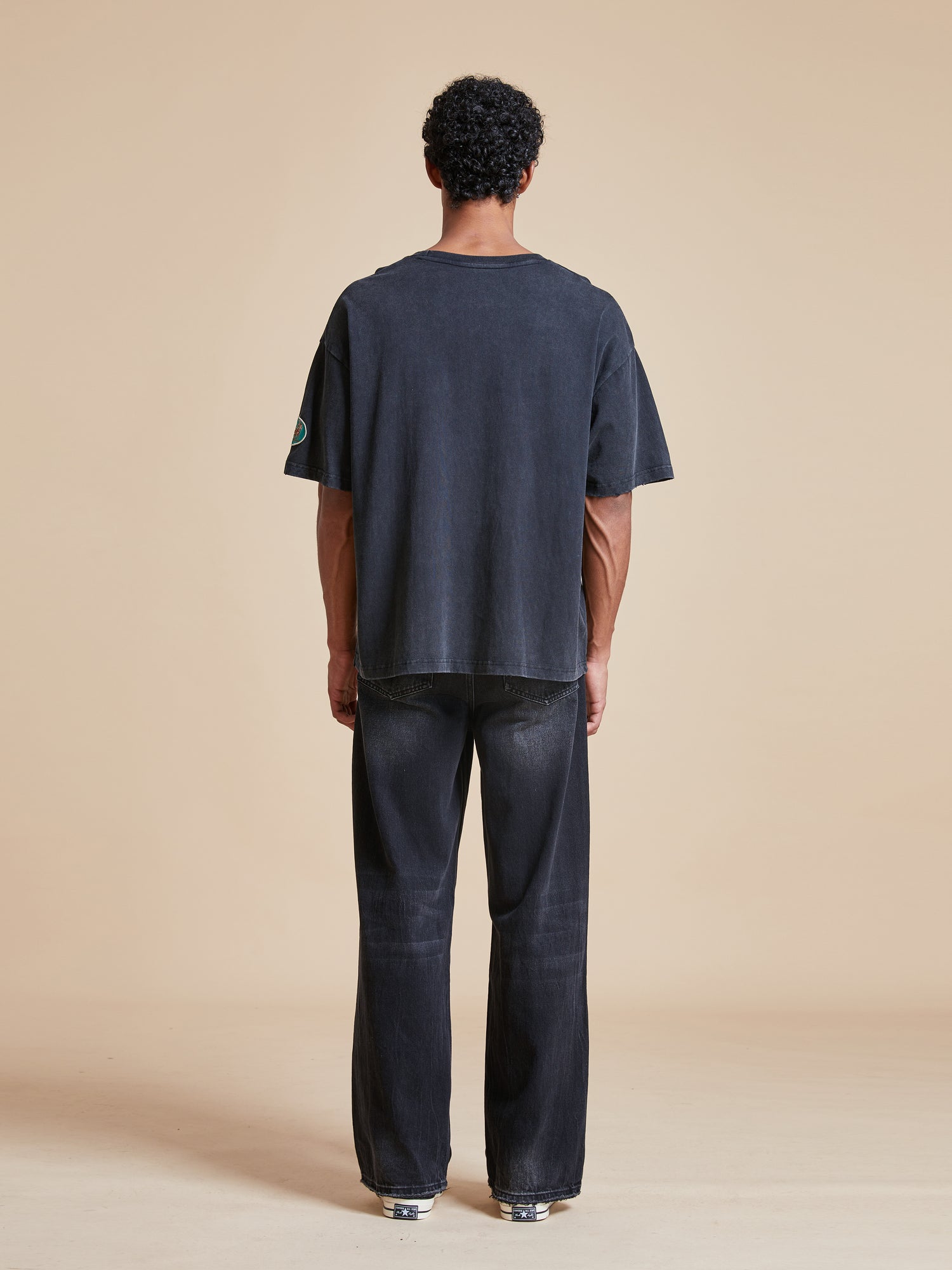 The back of a man wearing a Found Flowers Vase Tee.
