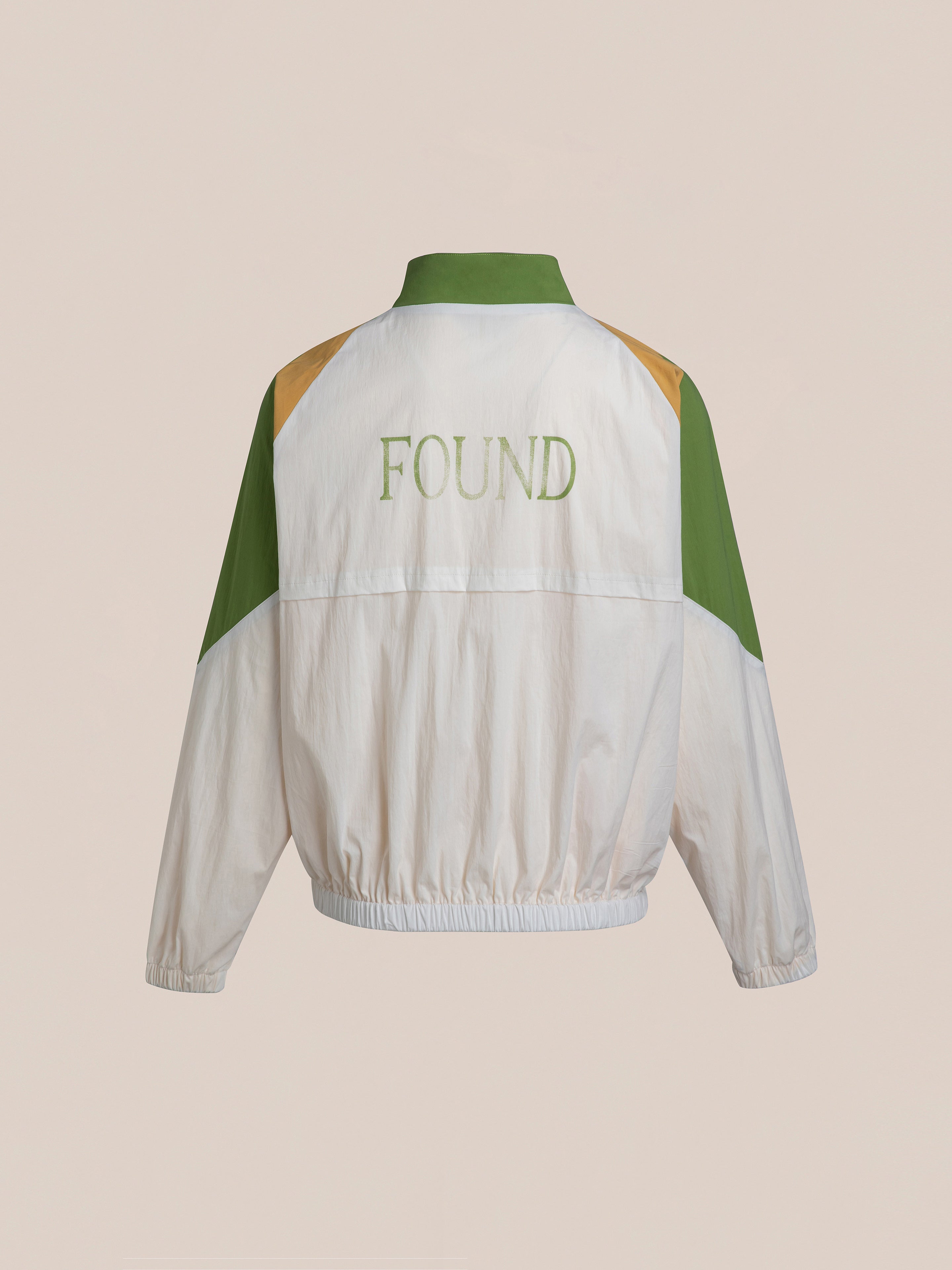 Back view of the Legacy Cricket Track Jacket, featuring a white and green design with "FOUND" branded on it, reminiscent of vintage athletic gear.