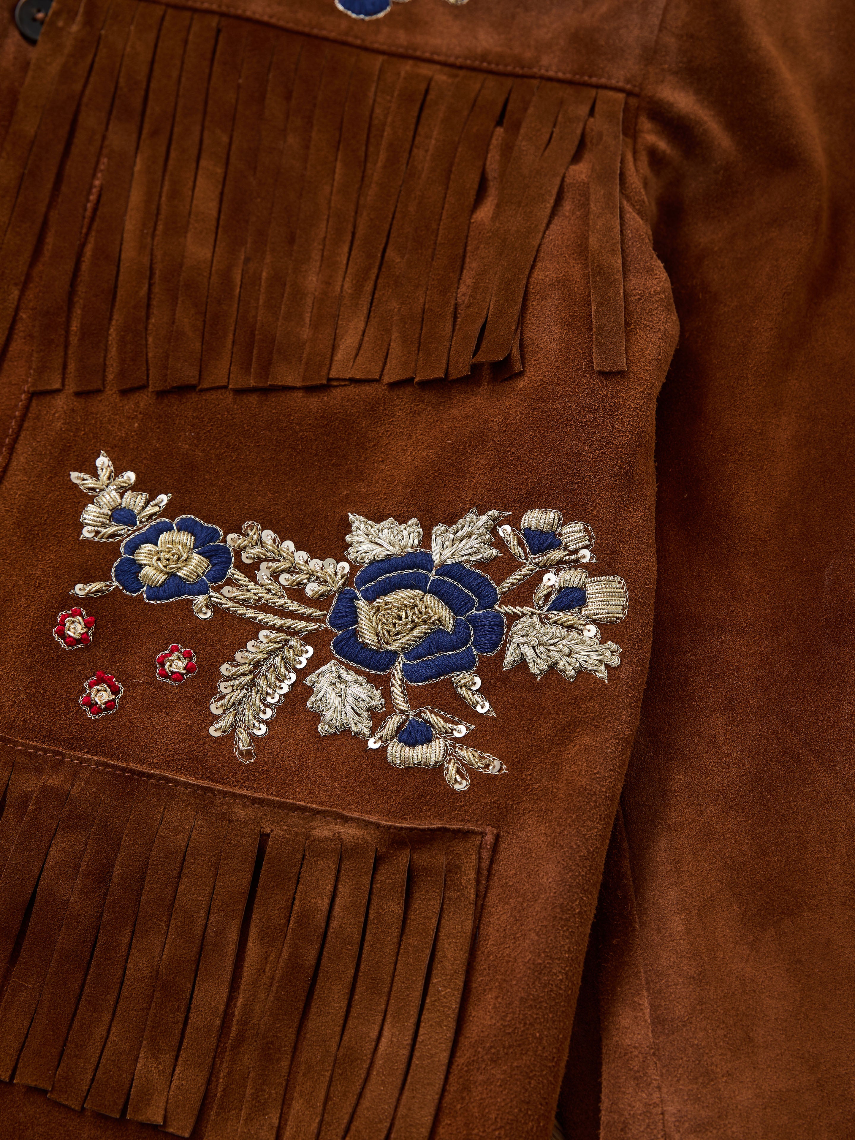 FOUND's Hand Embroidered Suede Fringe Jacket features exquisite blue, gold, and red floral embroidery on the sleeve—an eye-catching unisex statement piece for any stylish wardrobe.