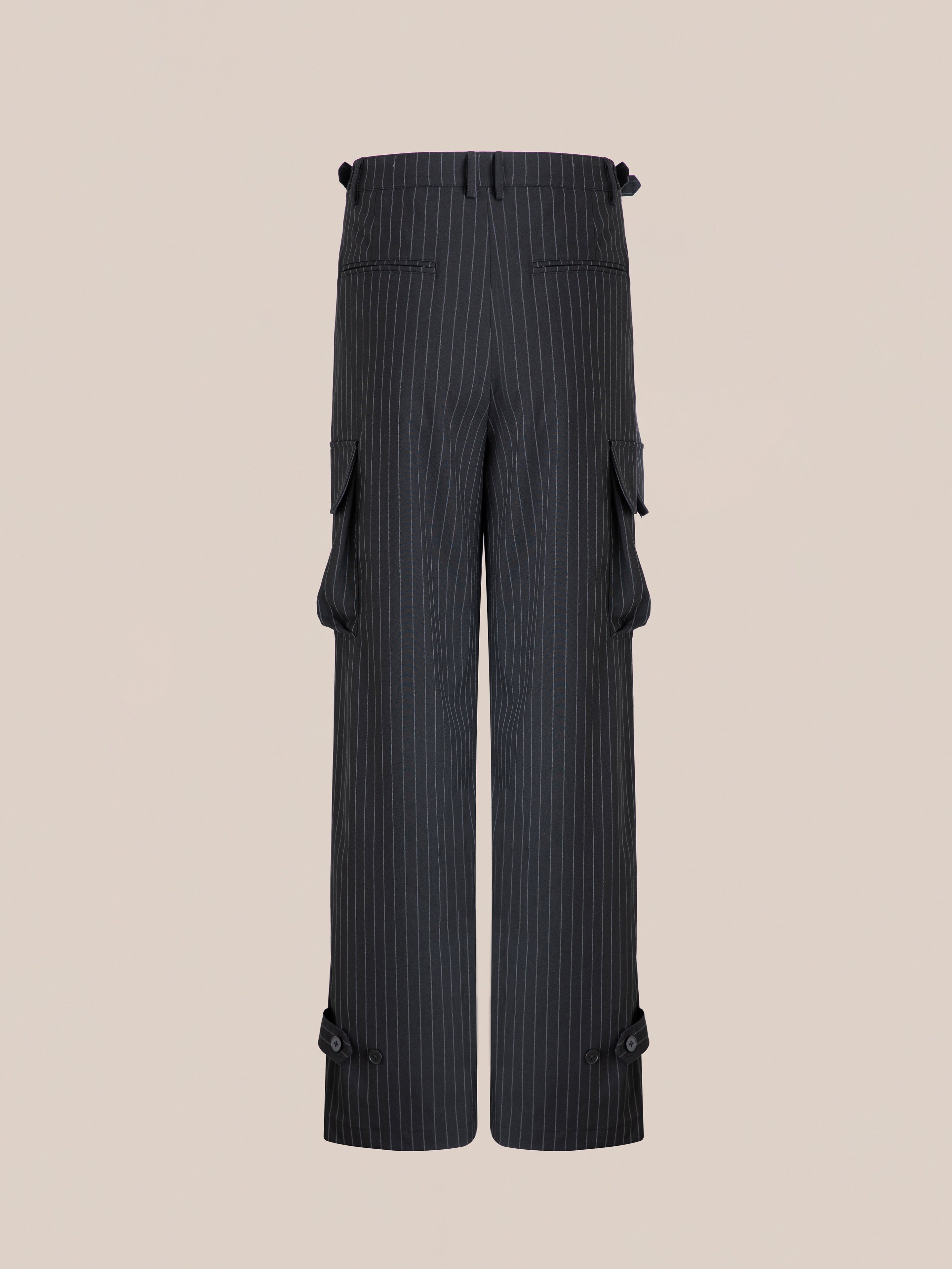 The Hava Pinstripe Pleated Cargo Trousers by FOUND in black wool-blend feature multiple pockets, hem-adjustable straps, and side tabs for a perfect fit, all set against a neutral backdrop.