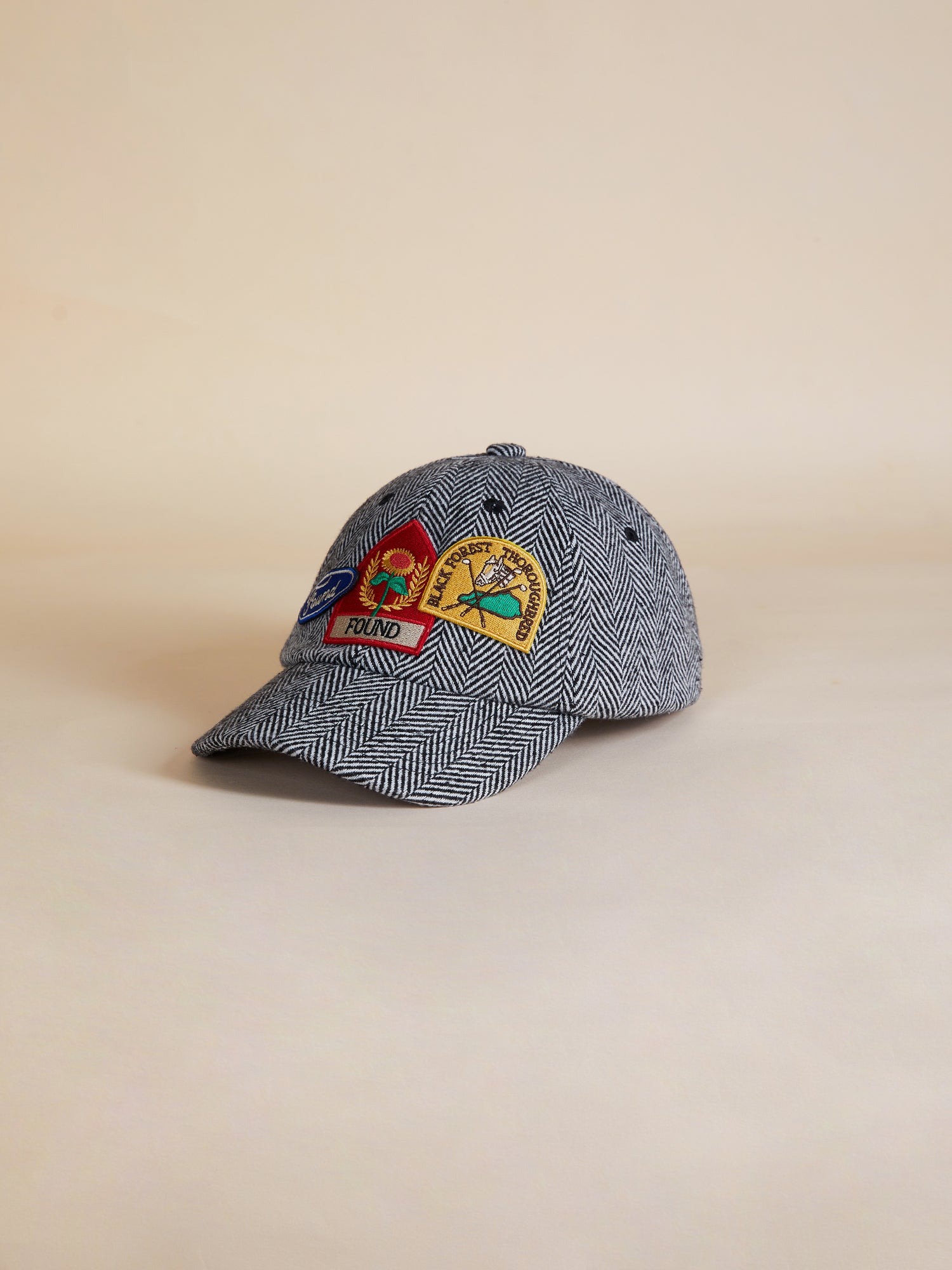 A Herringbone Tweed Patch Cap from Found, with embroidered patches on it.