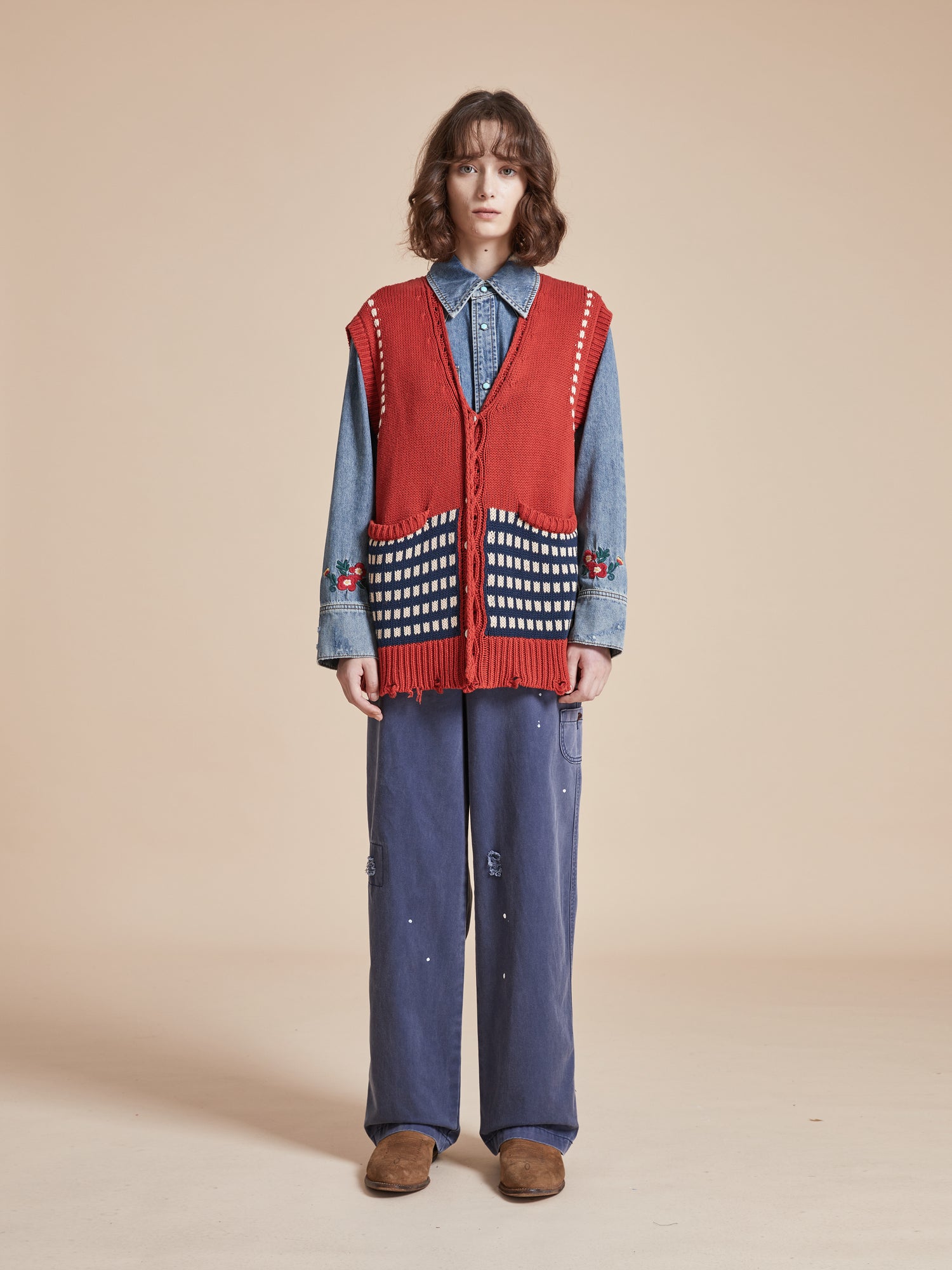A woman wearing a Homestead Check Sweater Knit Vest by Found and blue pants.