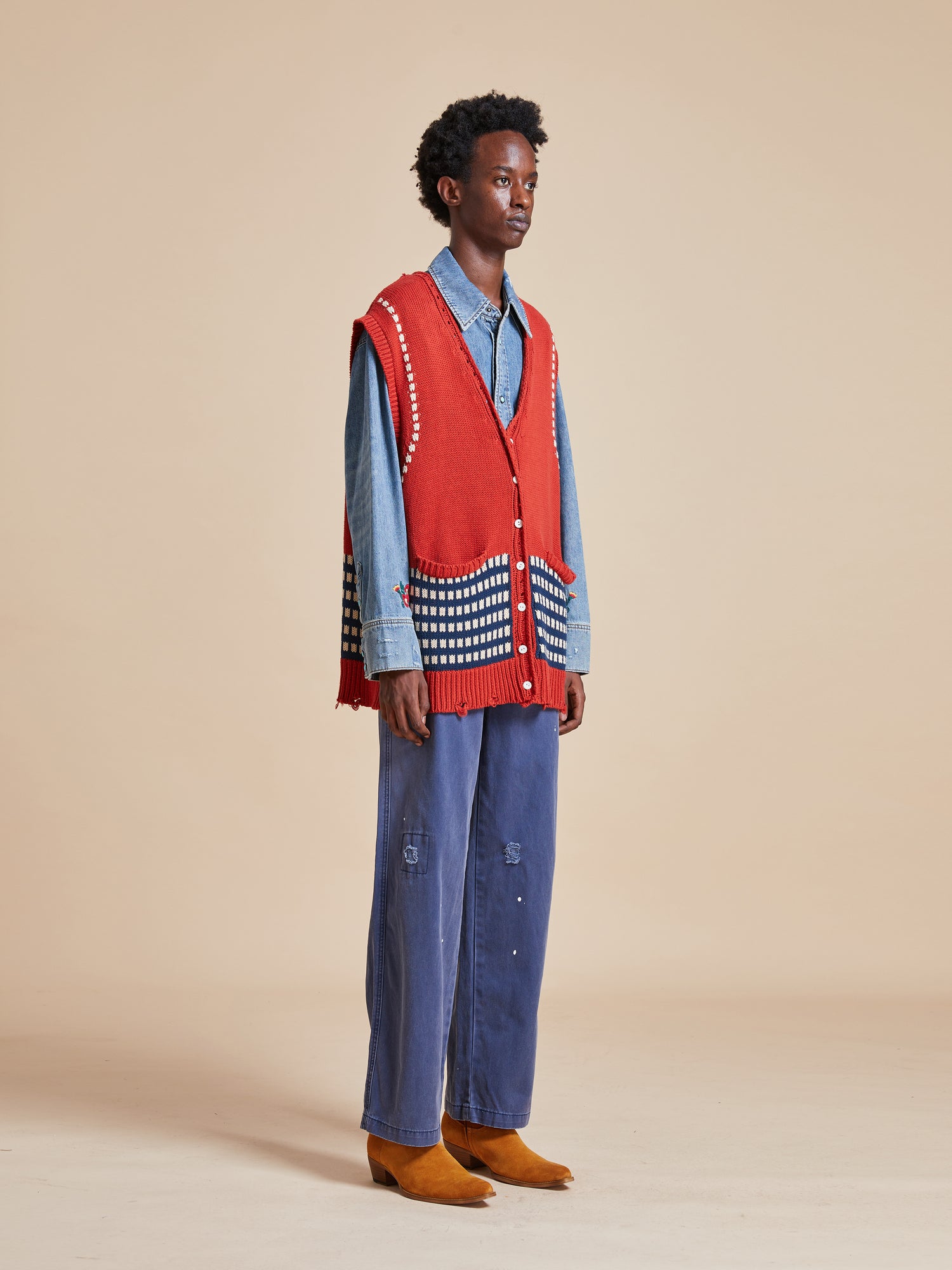 A man wearing a Homestead Check Sweater Knit Vest by Found and blue jeans.