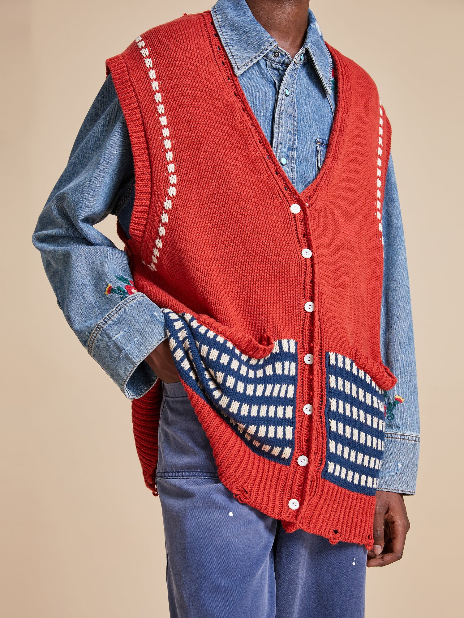 A man wearing a Found Homestead Check Sweater Knit Vest and blue jeans.