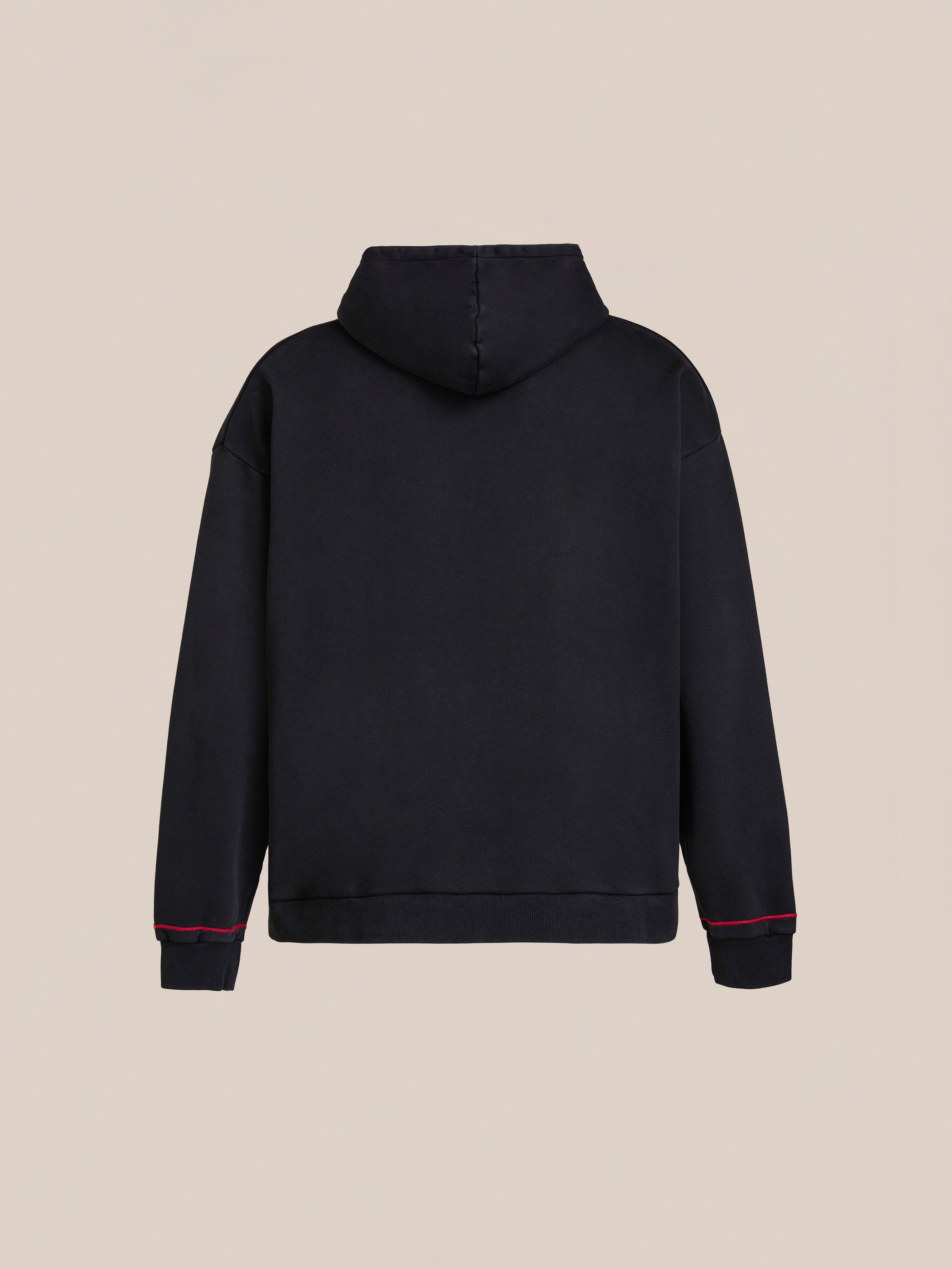 The FOUND Indus Embroidered Hoodie is shown from the back, featuring black fabric, long sleeves, and a red accent near the cuffs, displayed against a plain beige background.