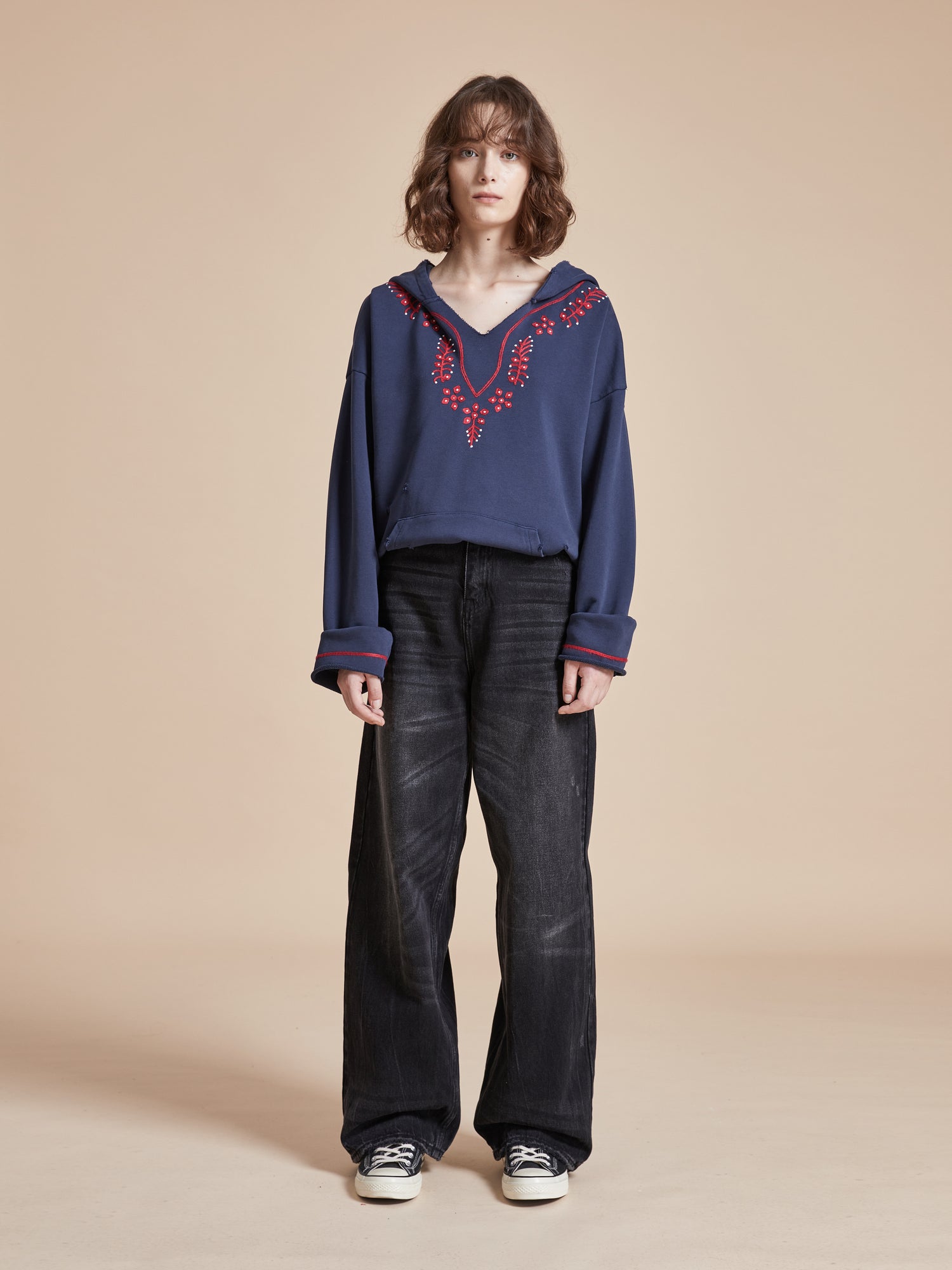 A model wearing a Found Indus Embroidered Hoodie and black pants.