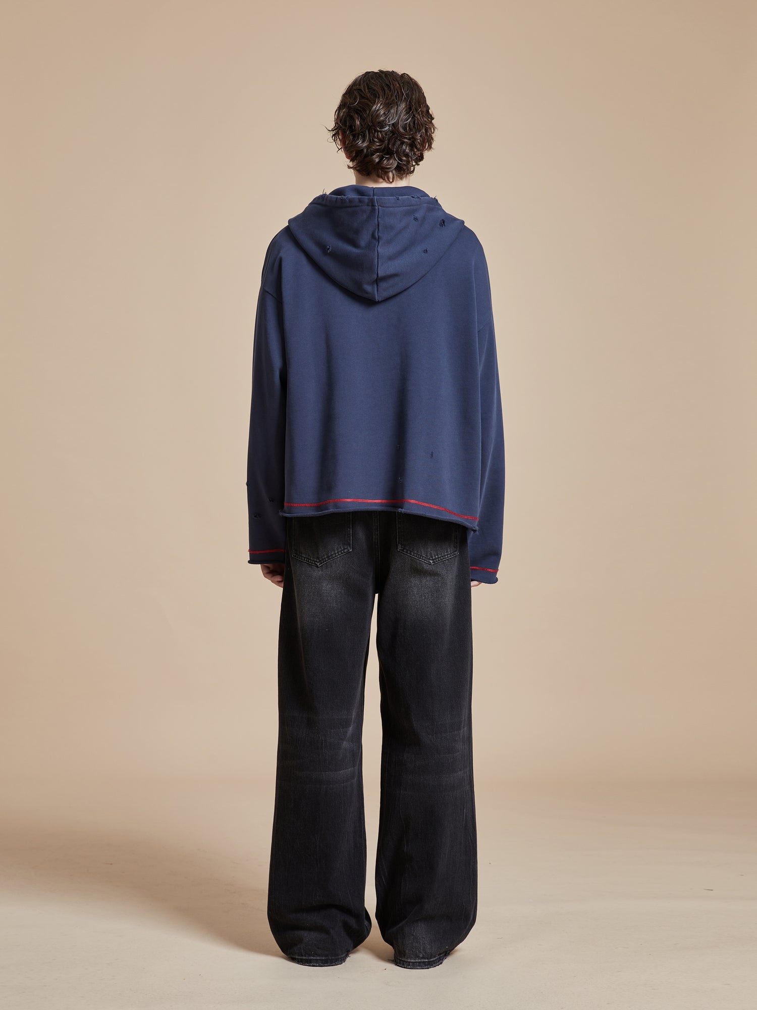 The back view of a man wearing a Found Indus Embroidered Hoodie and black pants.