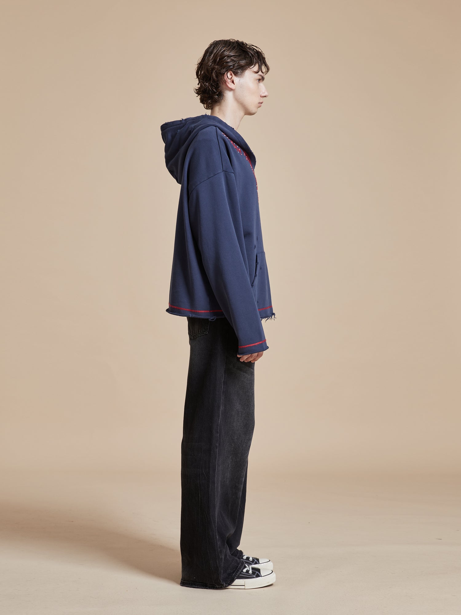 A model wearing a Indus Embroidered Hoodie by Found and black pants.