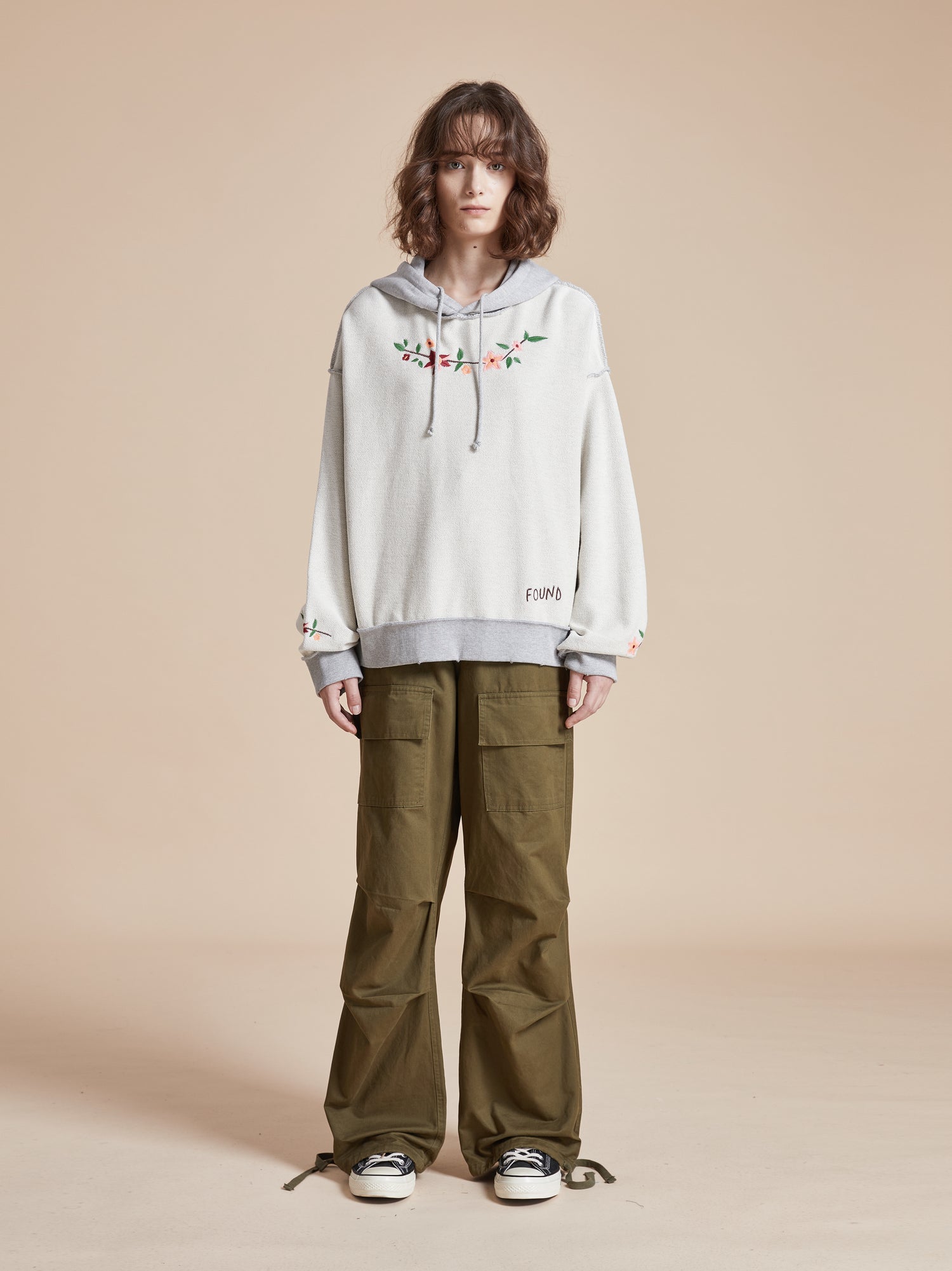 A woman wearing an Inverse Flower Petal Hoodie by Found and green pants.
