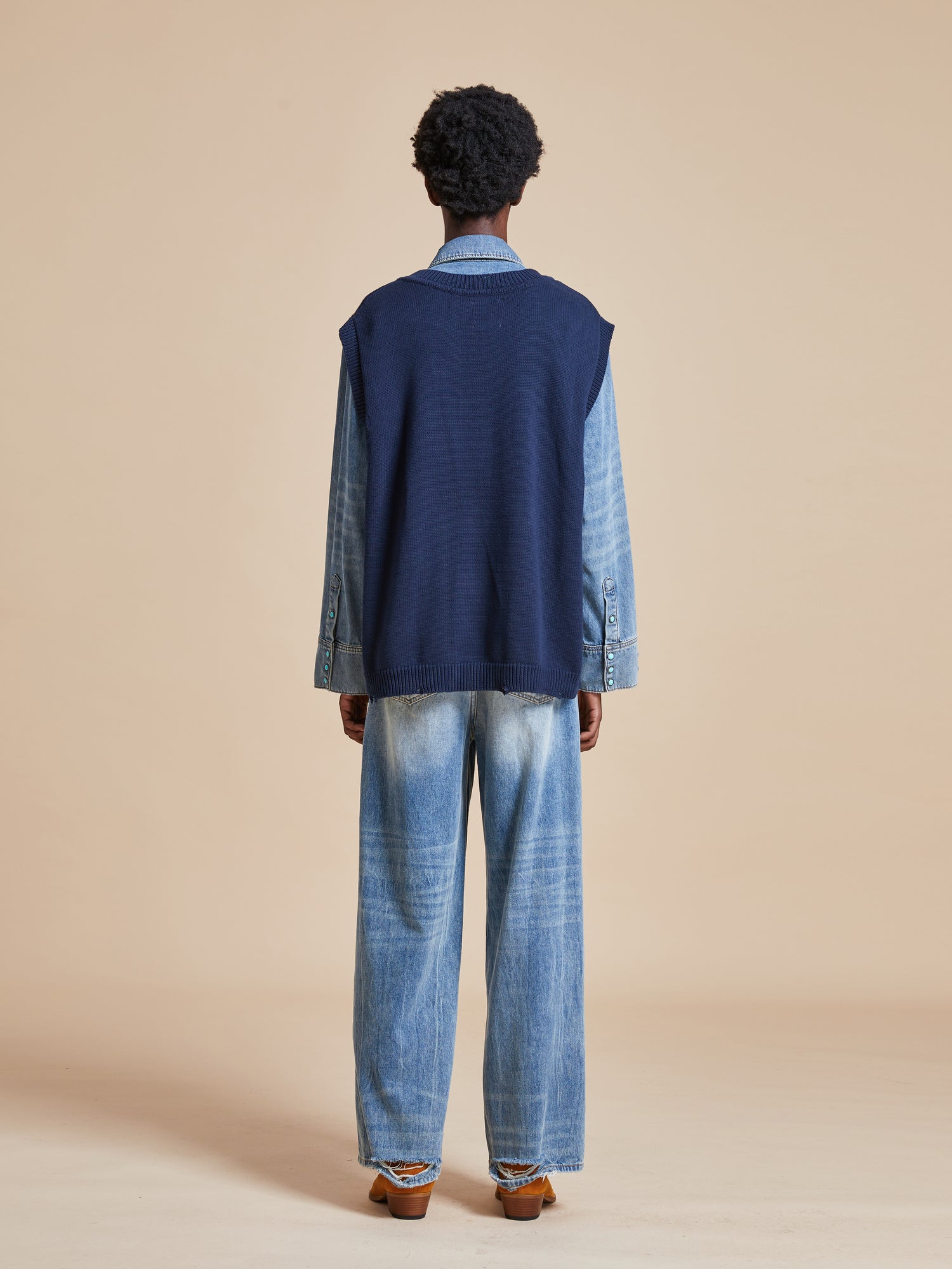 The back view of a man wearing a Found Isle Horse Reverie Sweater Knit Vest and jeans.
