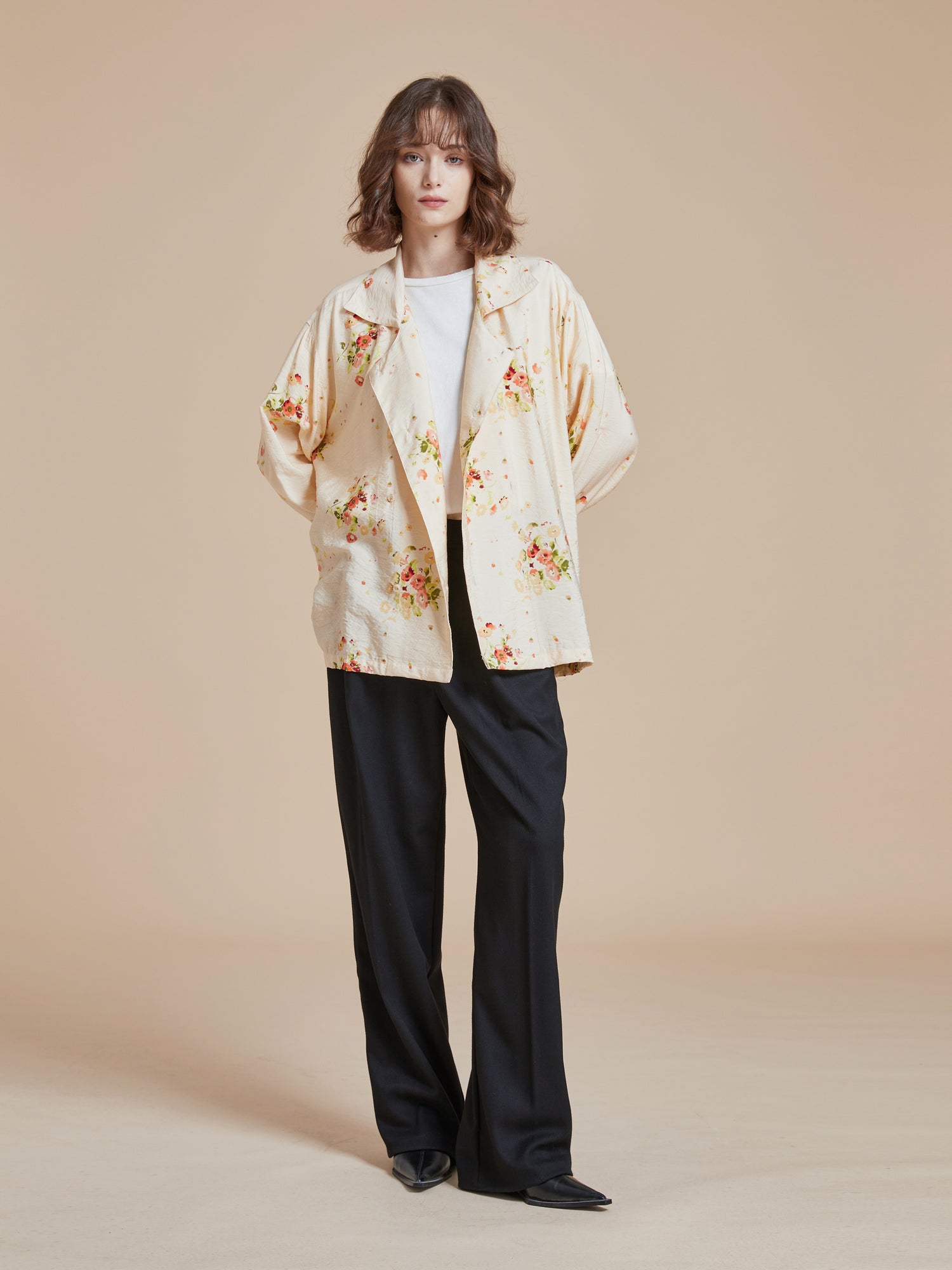 A model wearing a floral printed Found Kanhati Garden Long Sleeve Camp Shirt and black pants.