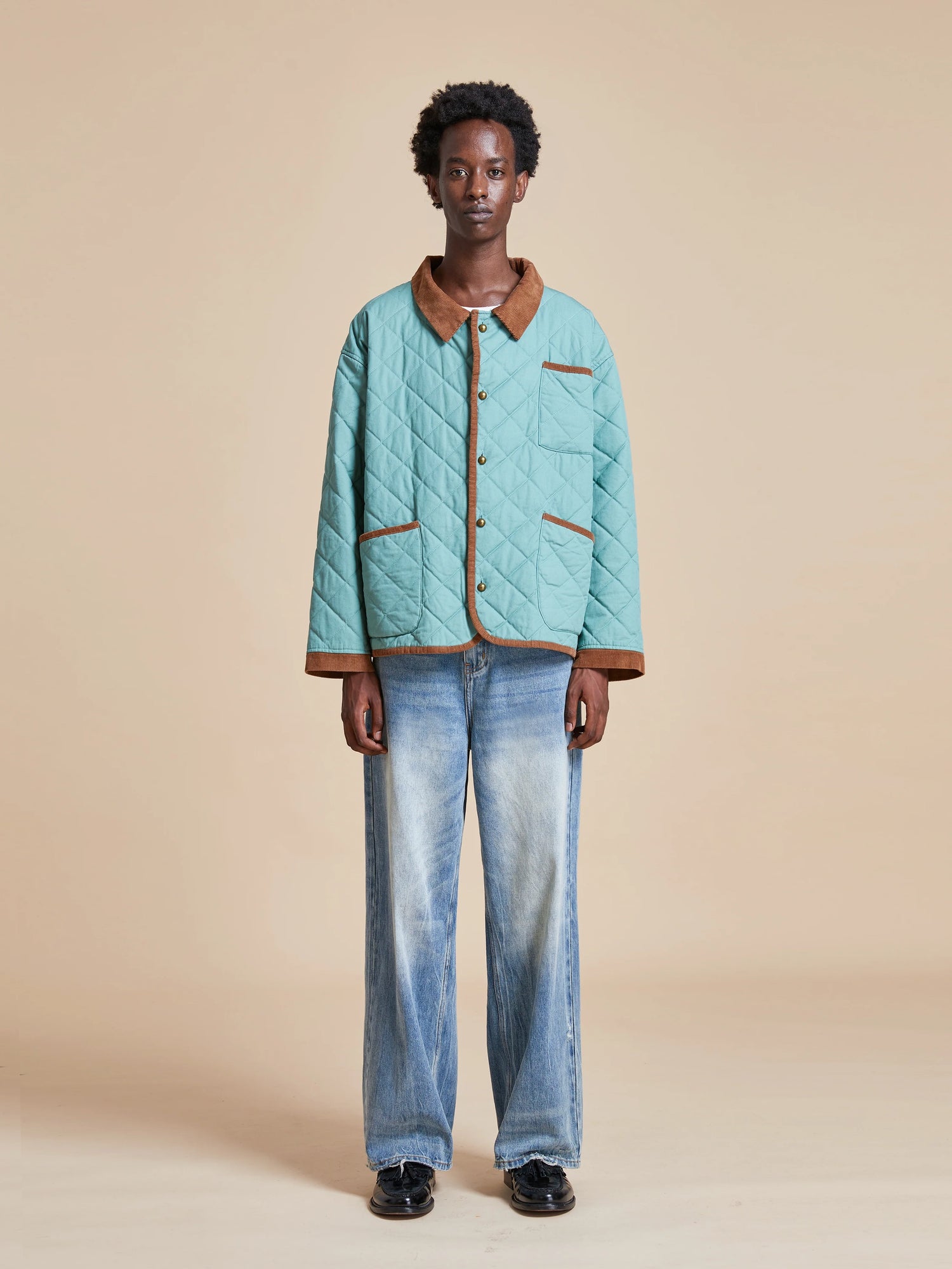 A man wearing a Found Kashmir Meadow Quilt Jacket and jeans.