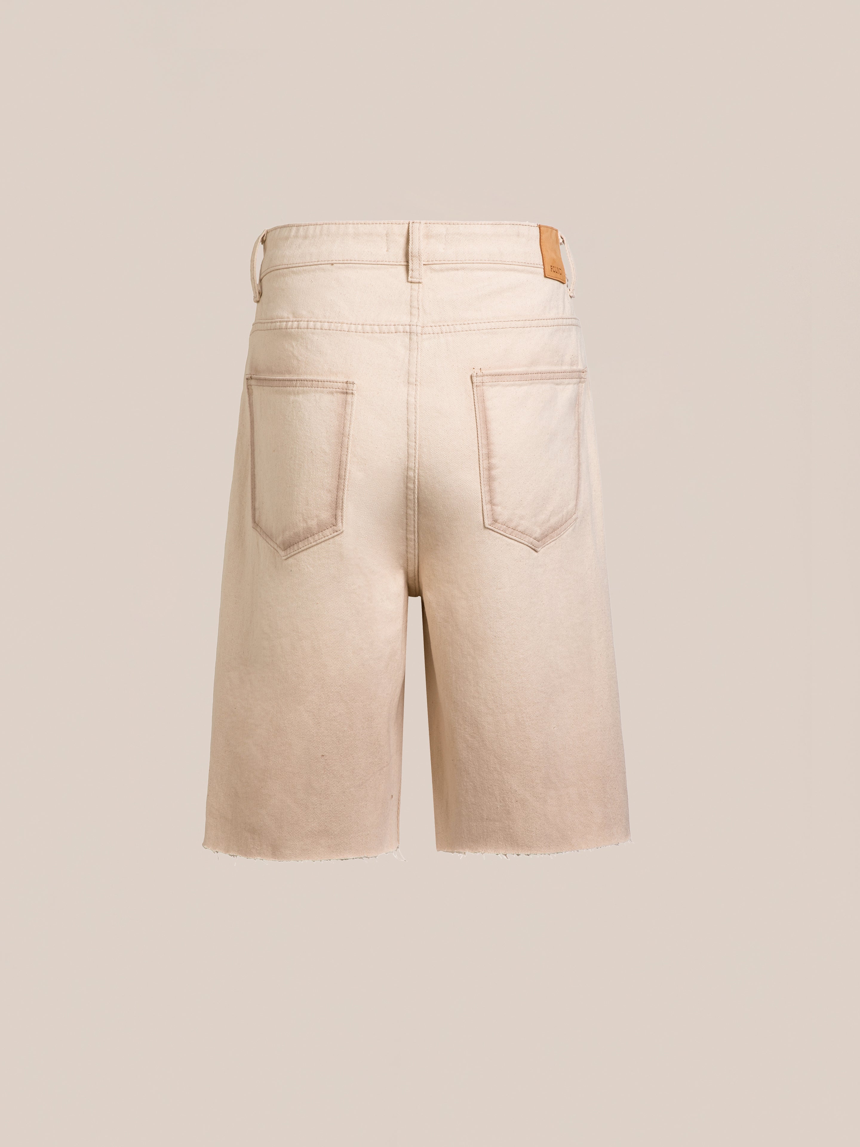 The FOUND Lacy Jean Jorts in beige are shown from the back, featuring two rear pockets, belt loops, and raw hems for a subtly distressed denim look against a plain background.