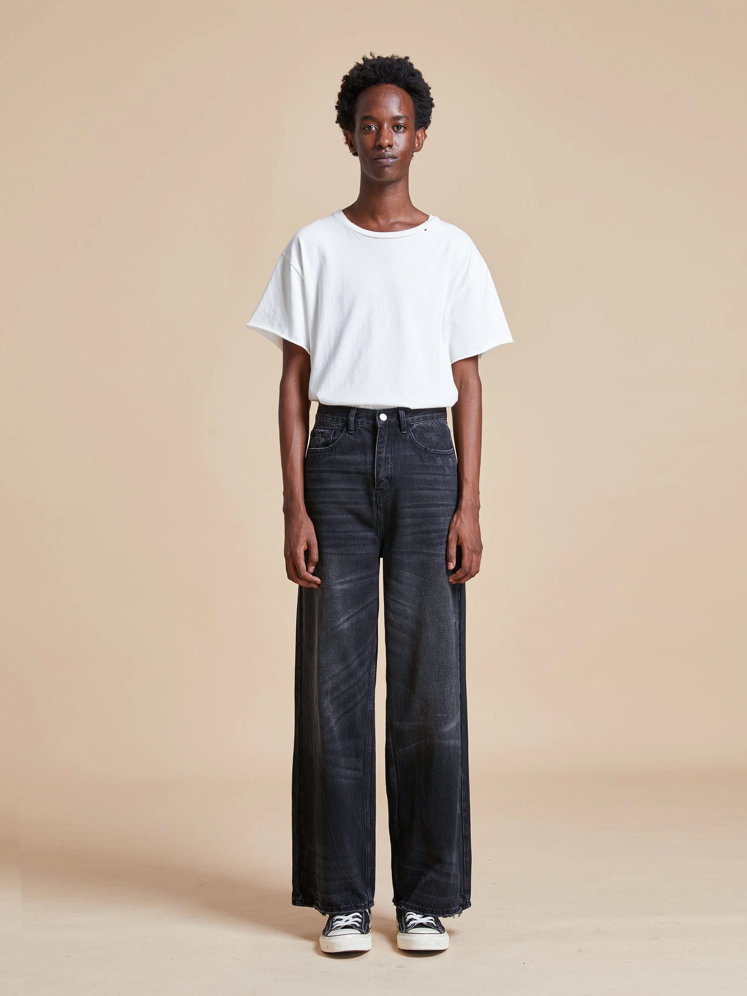 A model wearing Found's Lacy Baggy Jeans with distressed hems and a white t-shirt.