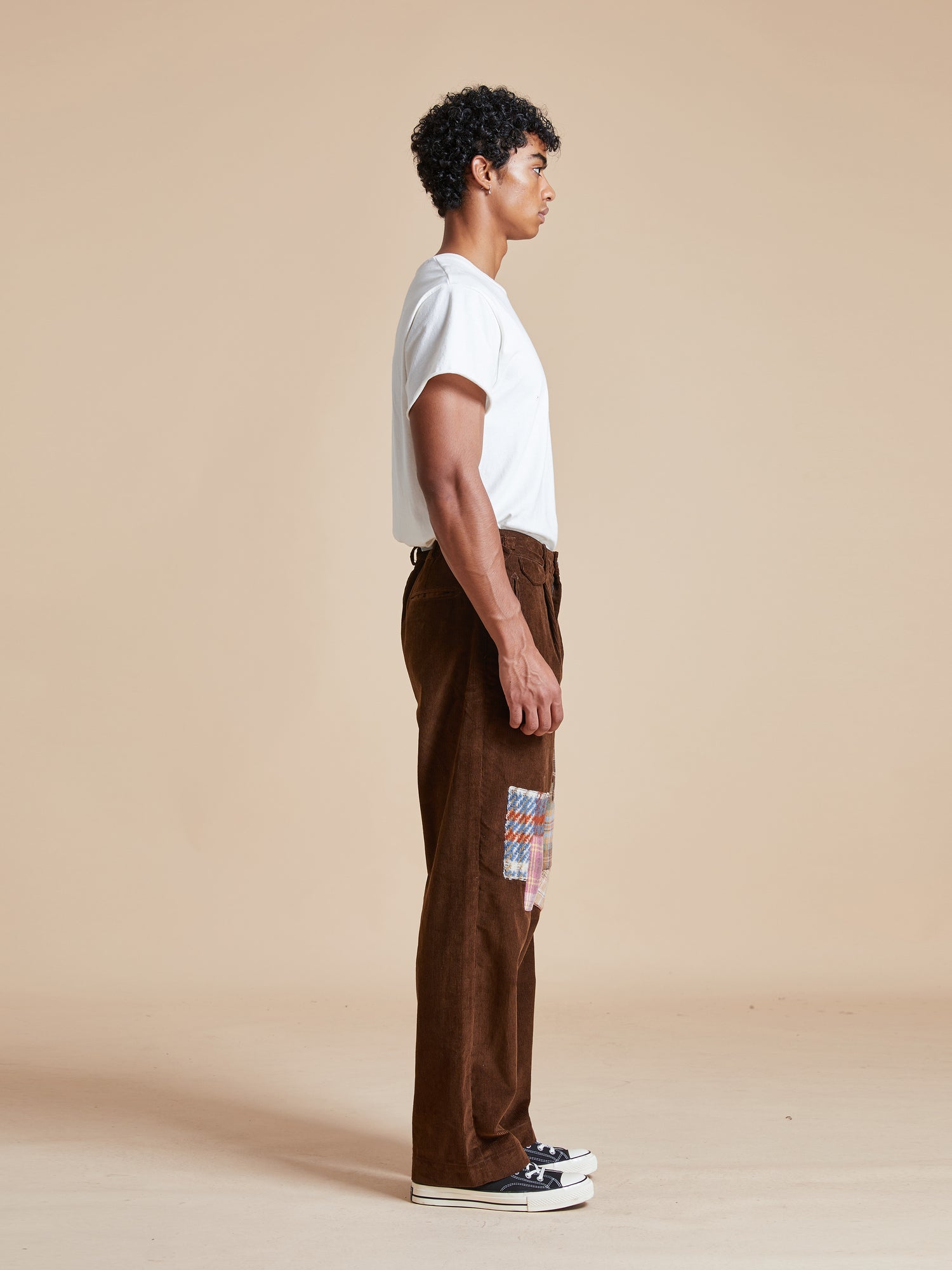 A man wearing Found Multi-Plaid Patch Corduroy Pants with fabric patches.