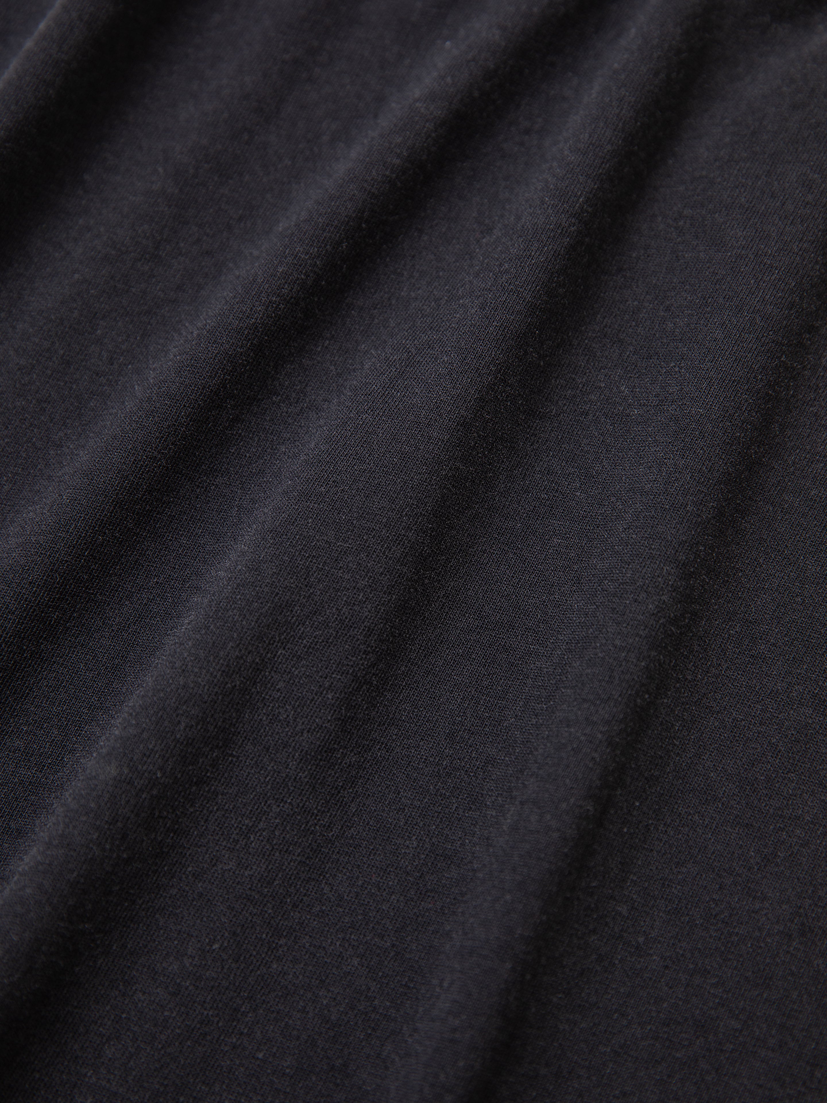 Close-up of the FOUND Multi Patch Washed Tee in black, showcasing its folds and texture.
