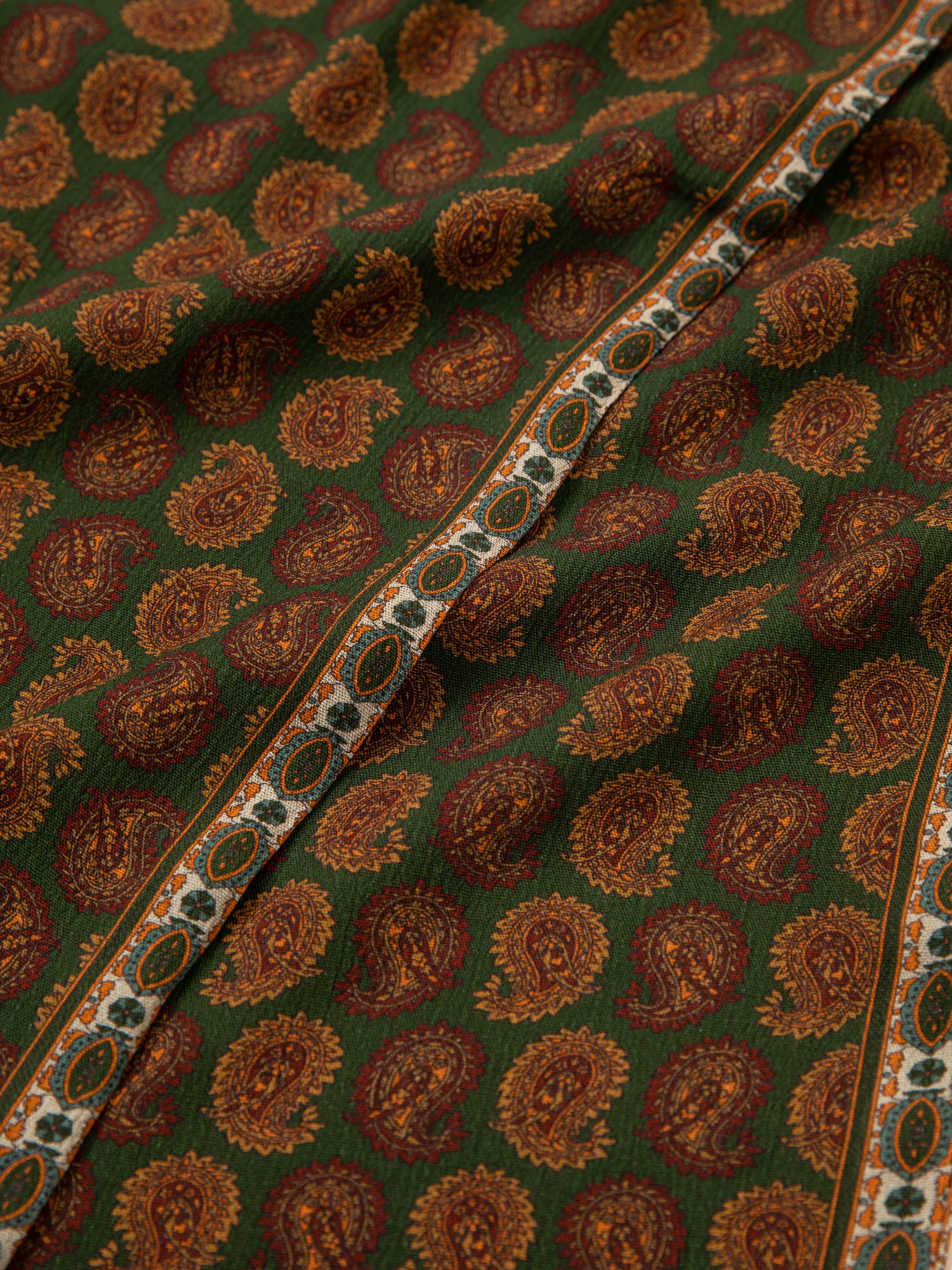 A close up of a Found Paisley Forest Scarf with a paisley print fabric and hand-tied tassels.