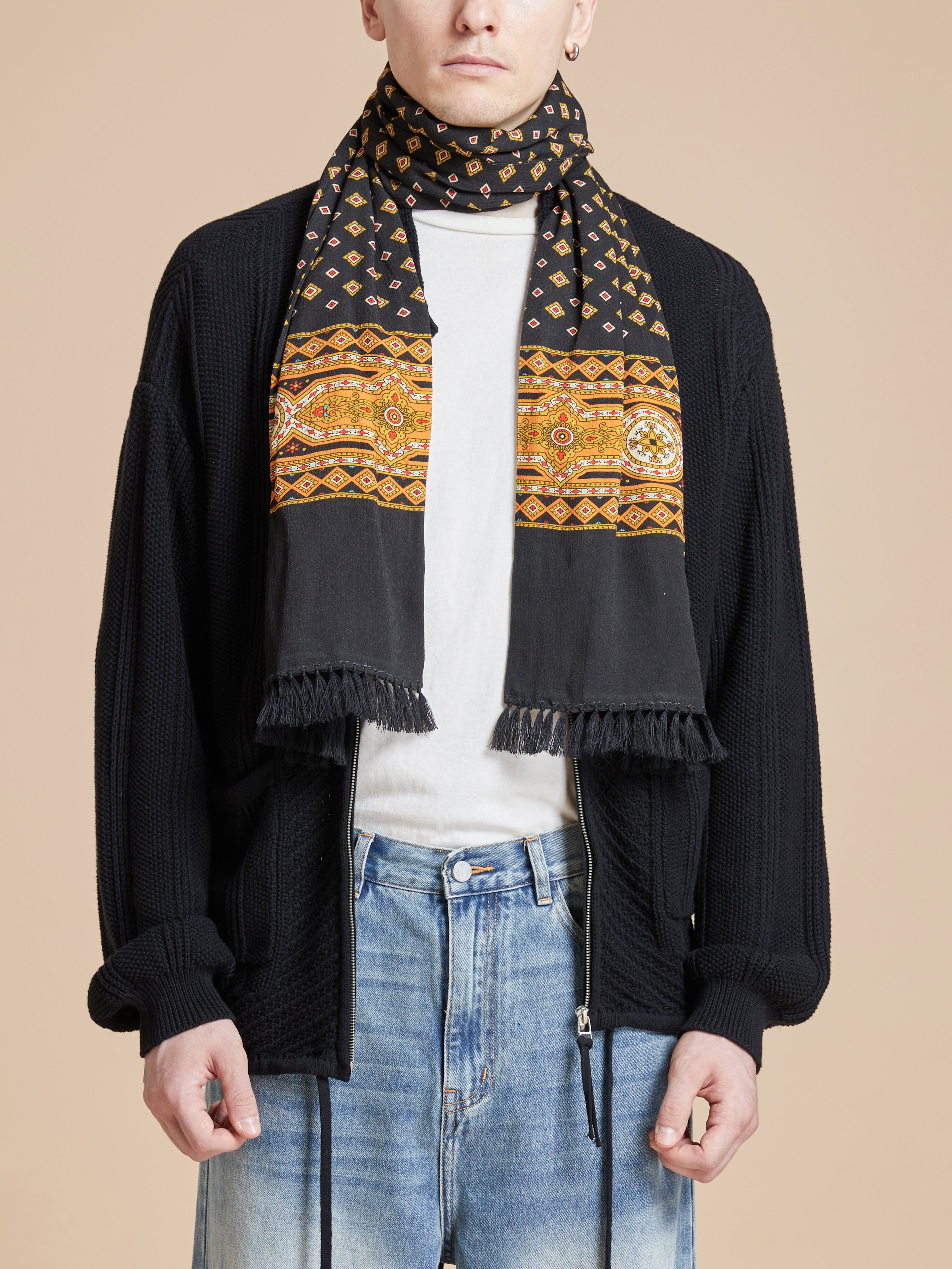 A man wearing a Found Pastures Print Scarf with hand-tied tassels.
