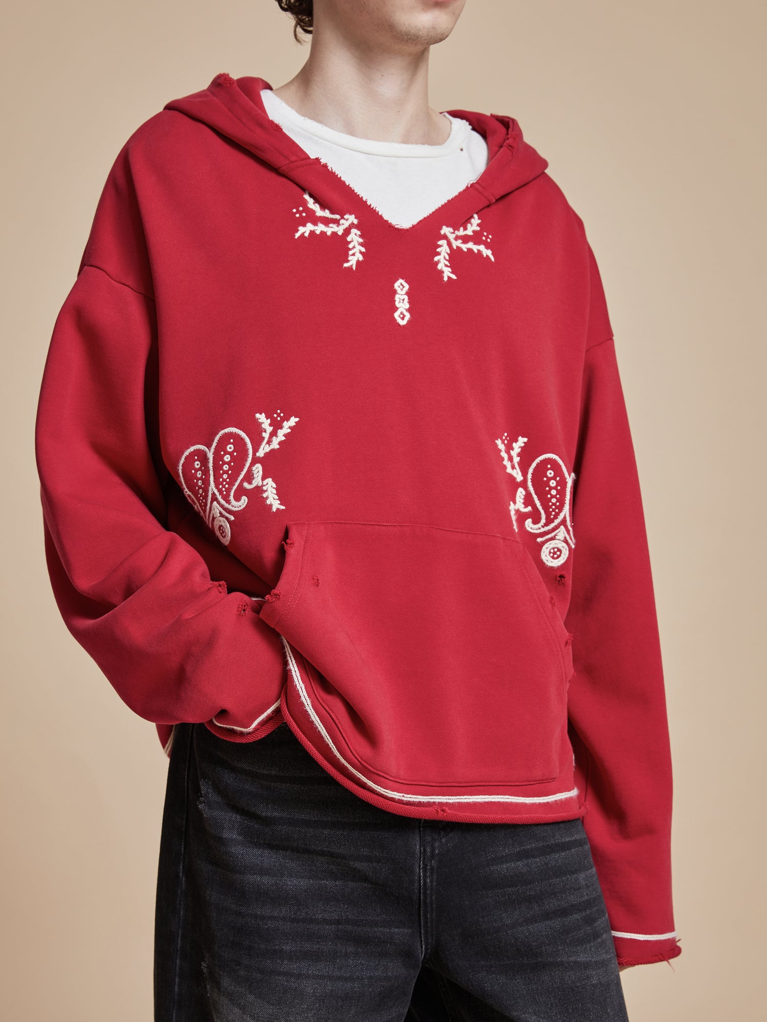 A man wearing a Found Phulkari Embroidered Hoodie and jeans.