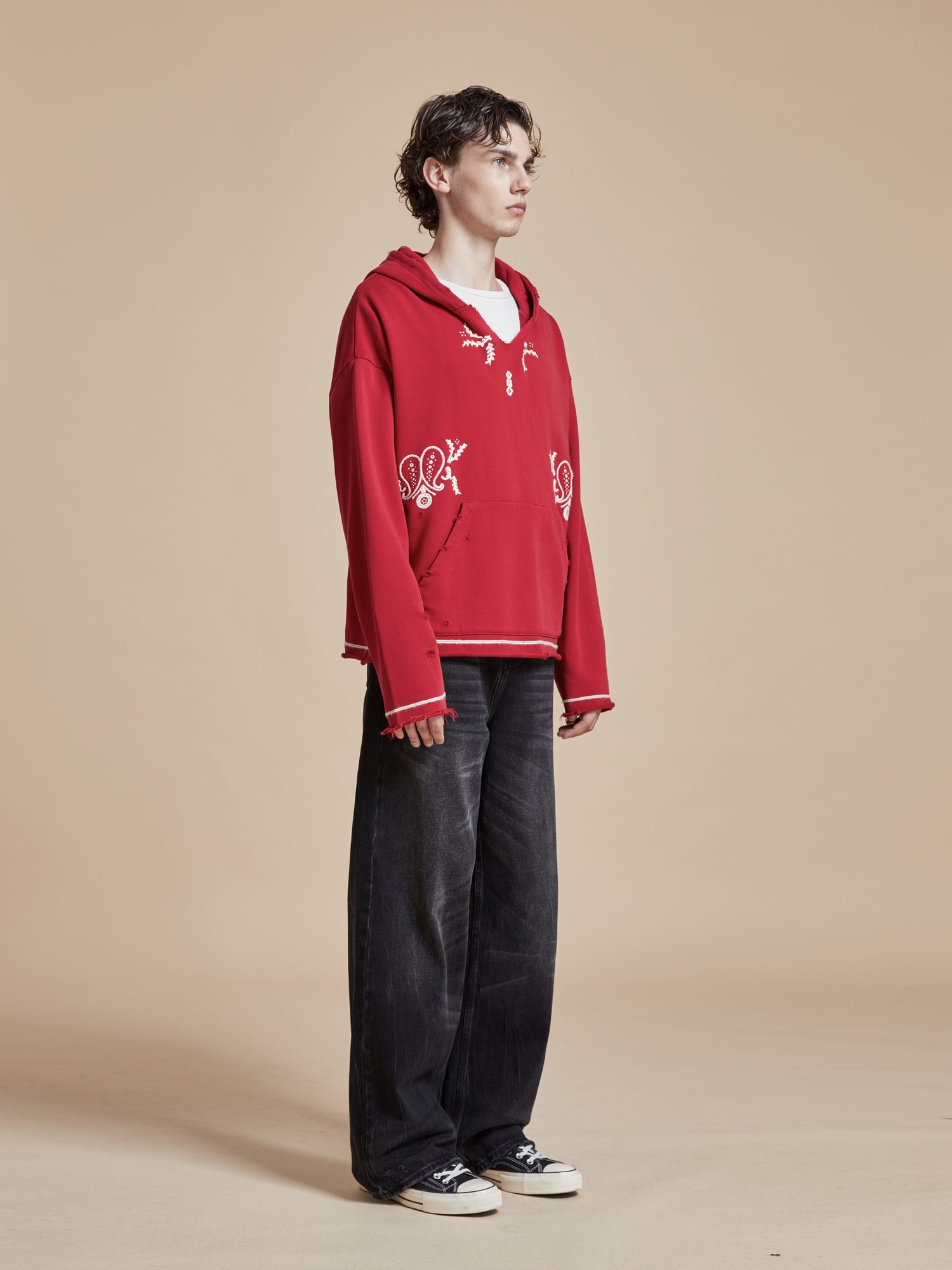 A man wearing a Found Phulkari Embroidered Hoodie and black pants.