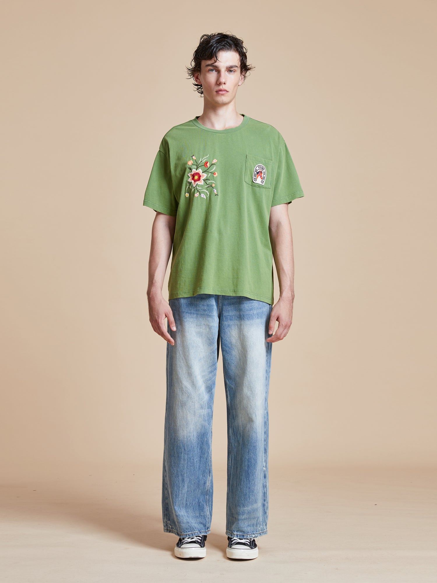 A man wearing a Pine Needle Farm Tee by Found and jeans.