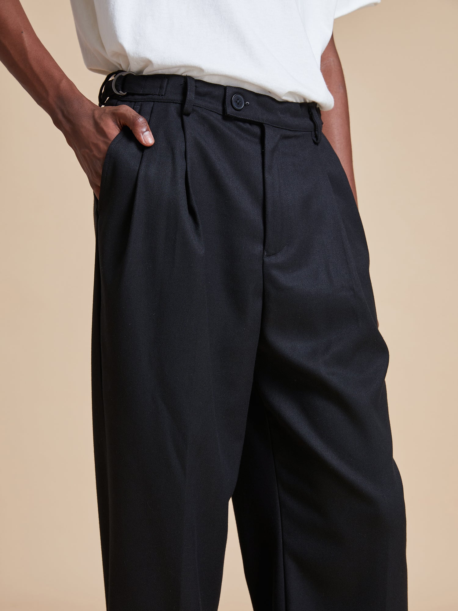 A man wearing Found pleated trousers and a white t - shirt.