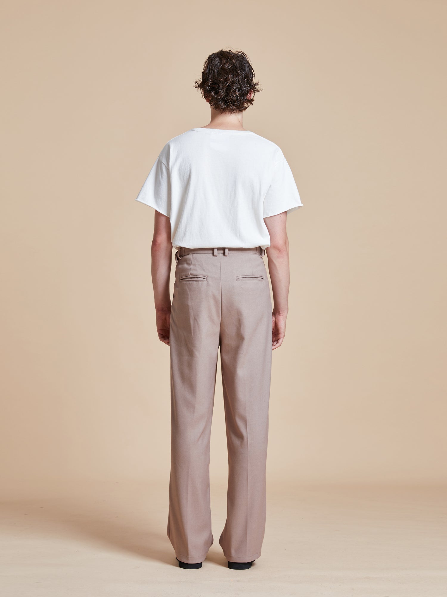 The back view of a man wearing Found Pleated Trousers.