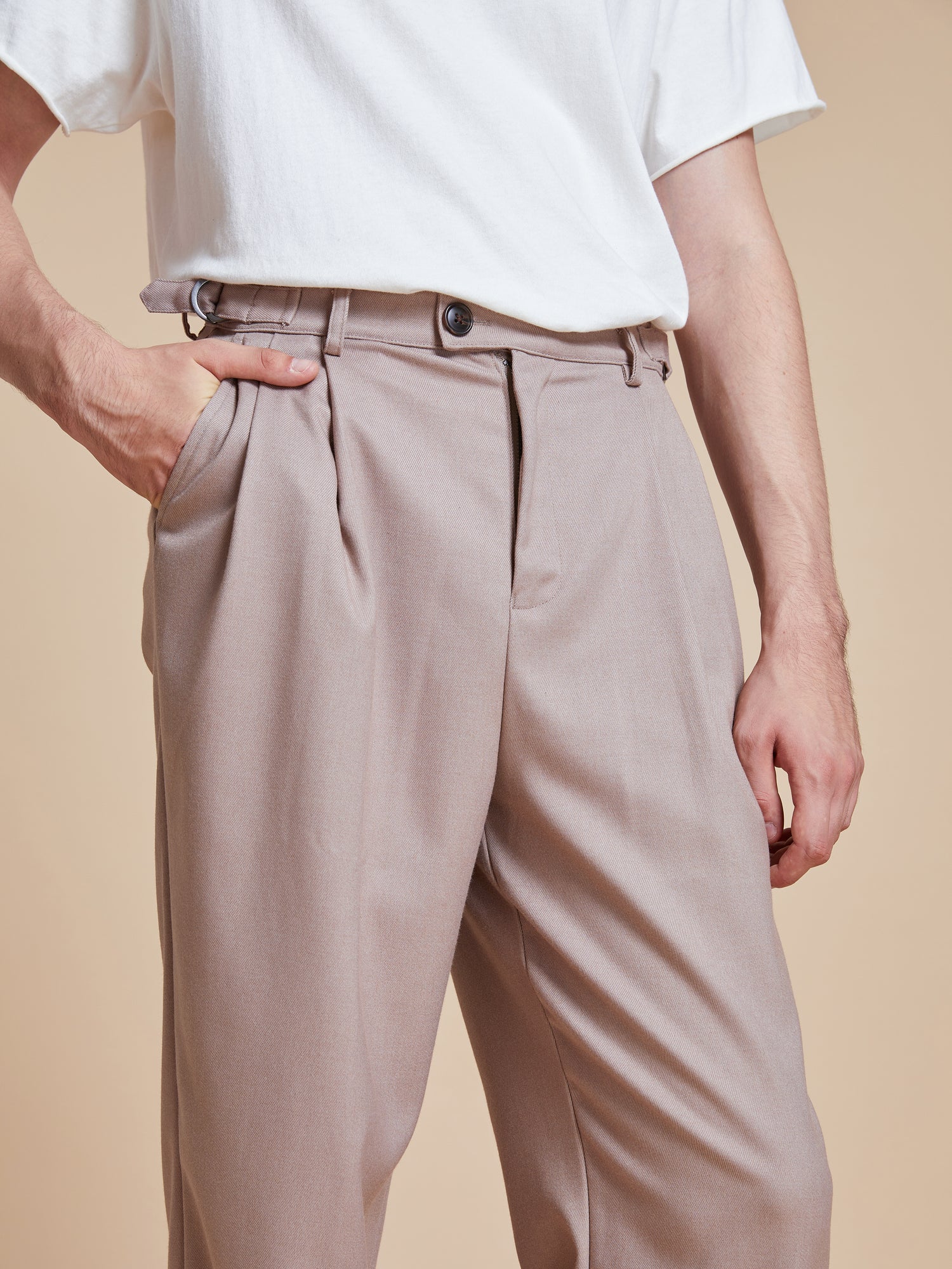A man wearing a white t-shirt and Found pleated trousers.