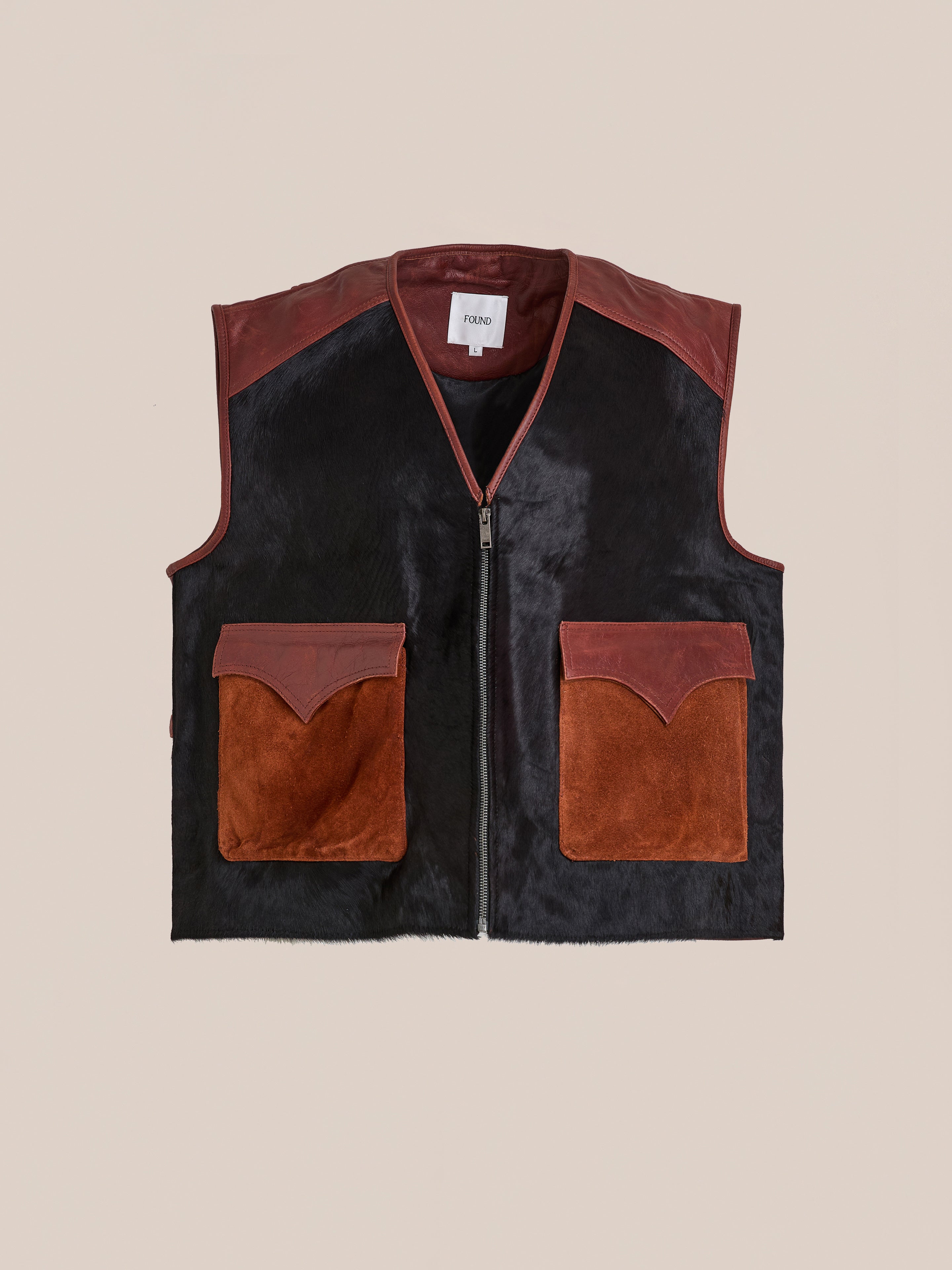 The Found Fur Western Leather Vest features black and brown panels, sleeveless zip-up design, two large brown front pockets, and leather trim on shoulders and pocket flaps.