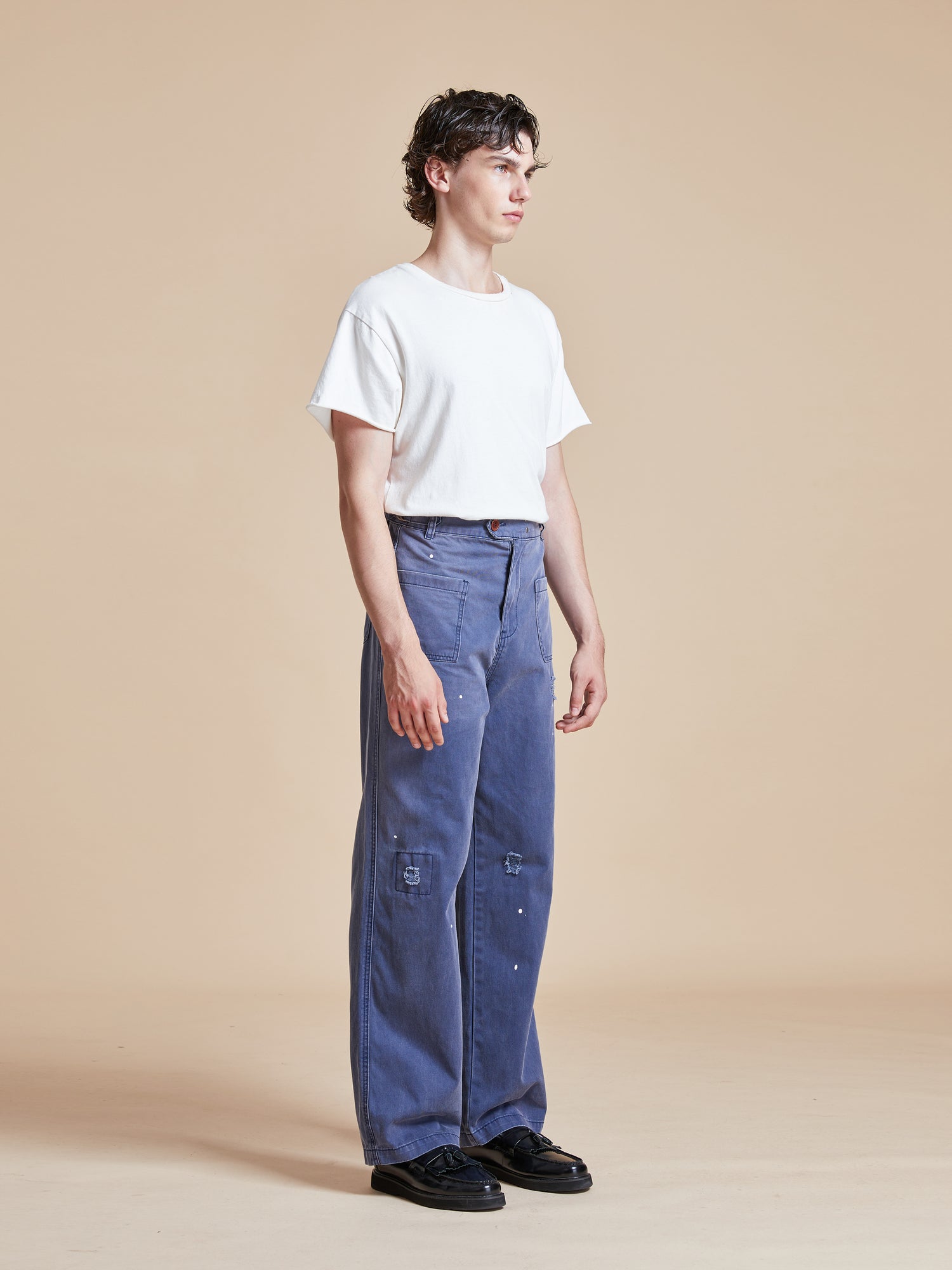 A man wearing River Painters Chore Pants and a white t - shirt.