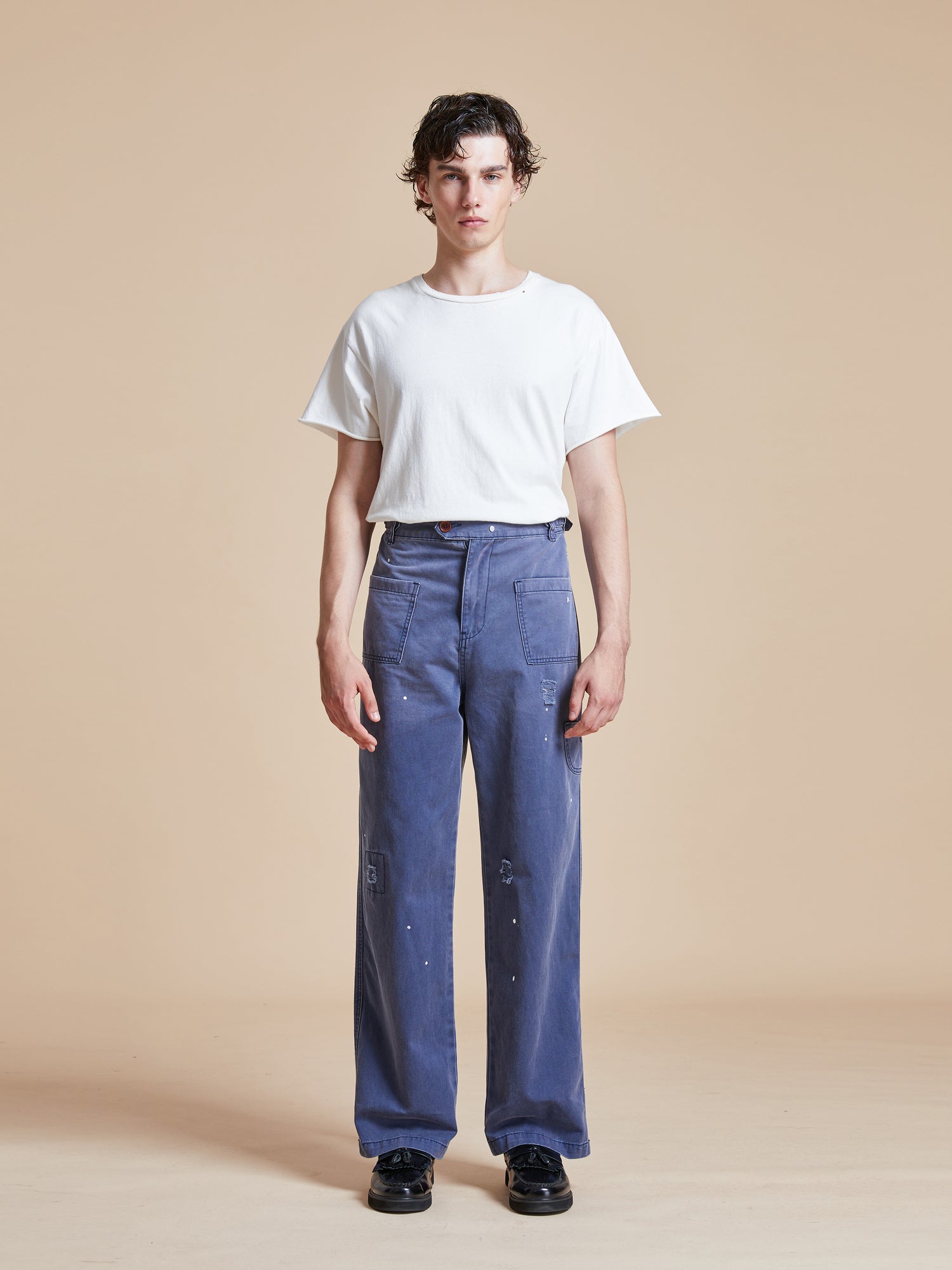 A man wearing River Painters Chore Pants from Found and a white t-shirt.
