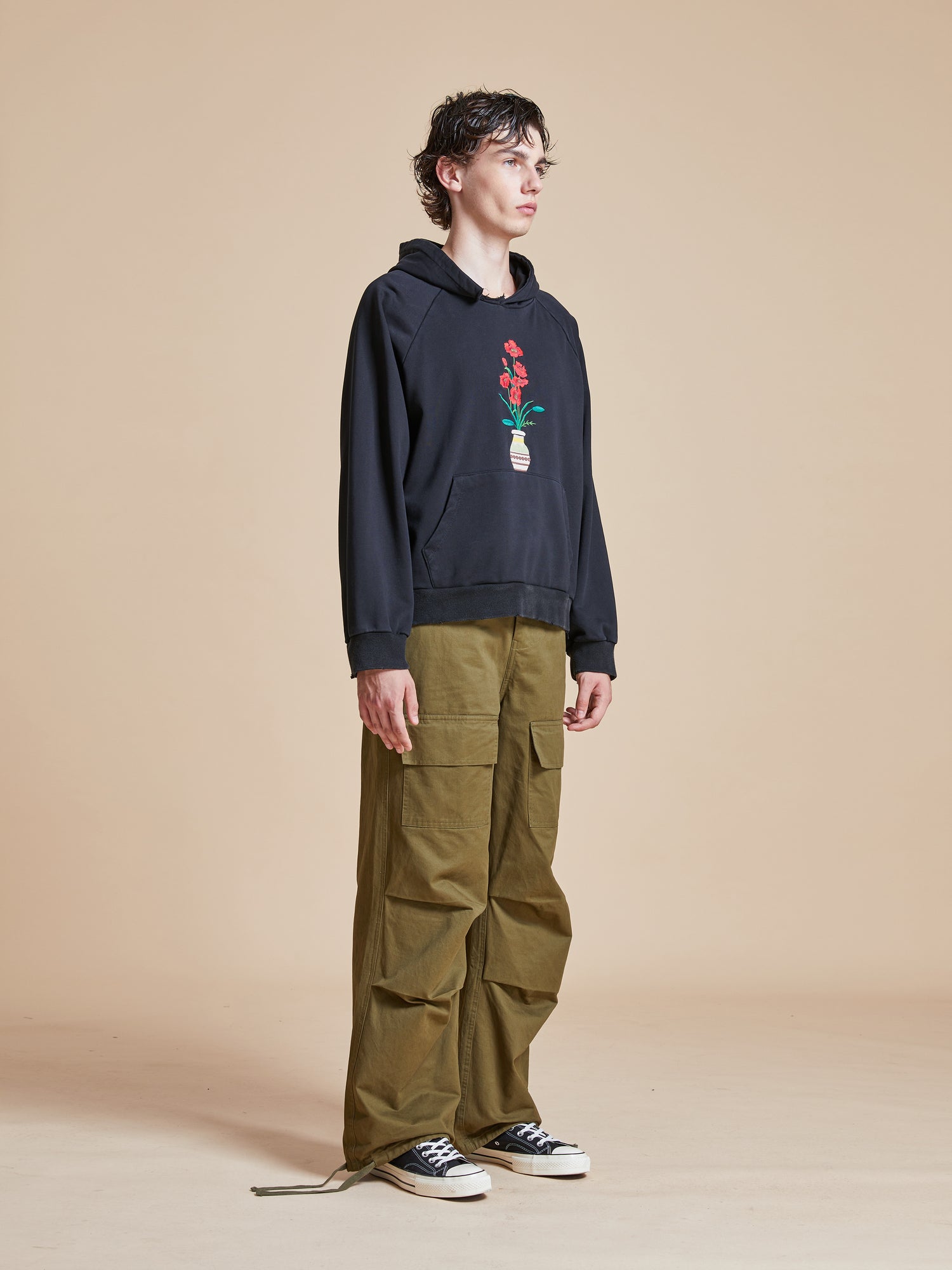 A man wearing a Found Flowers Vase Hoodie and cargo pants.