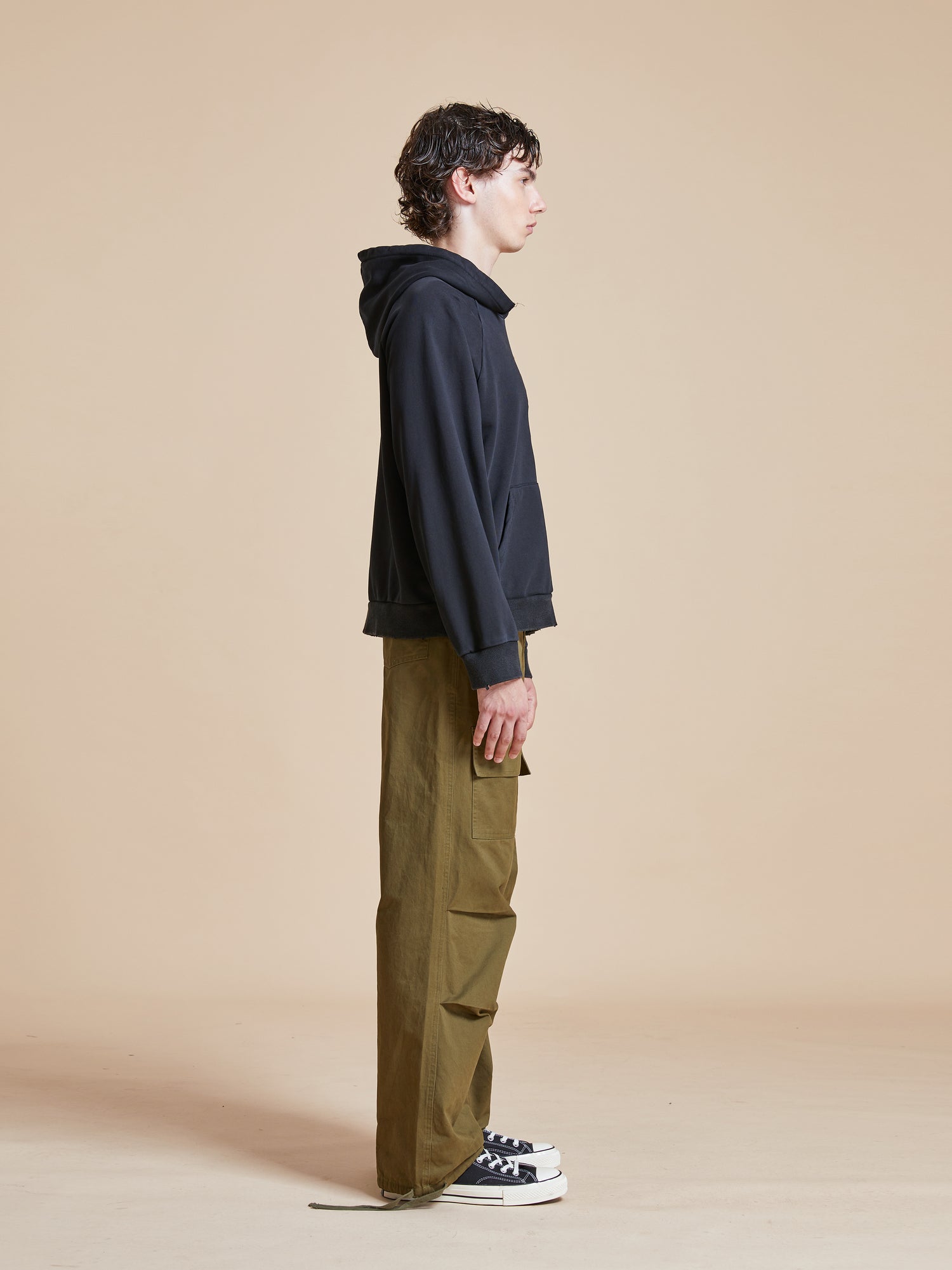 A man wearing a Found Flowers Vase Hoodie and cargo pants in olive green.
