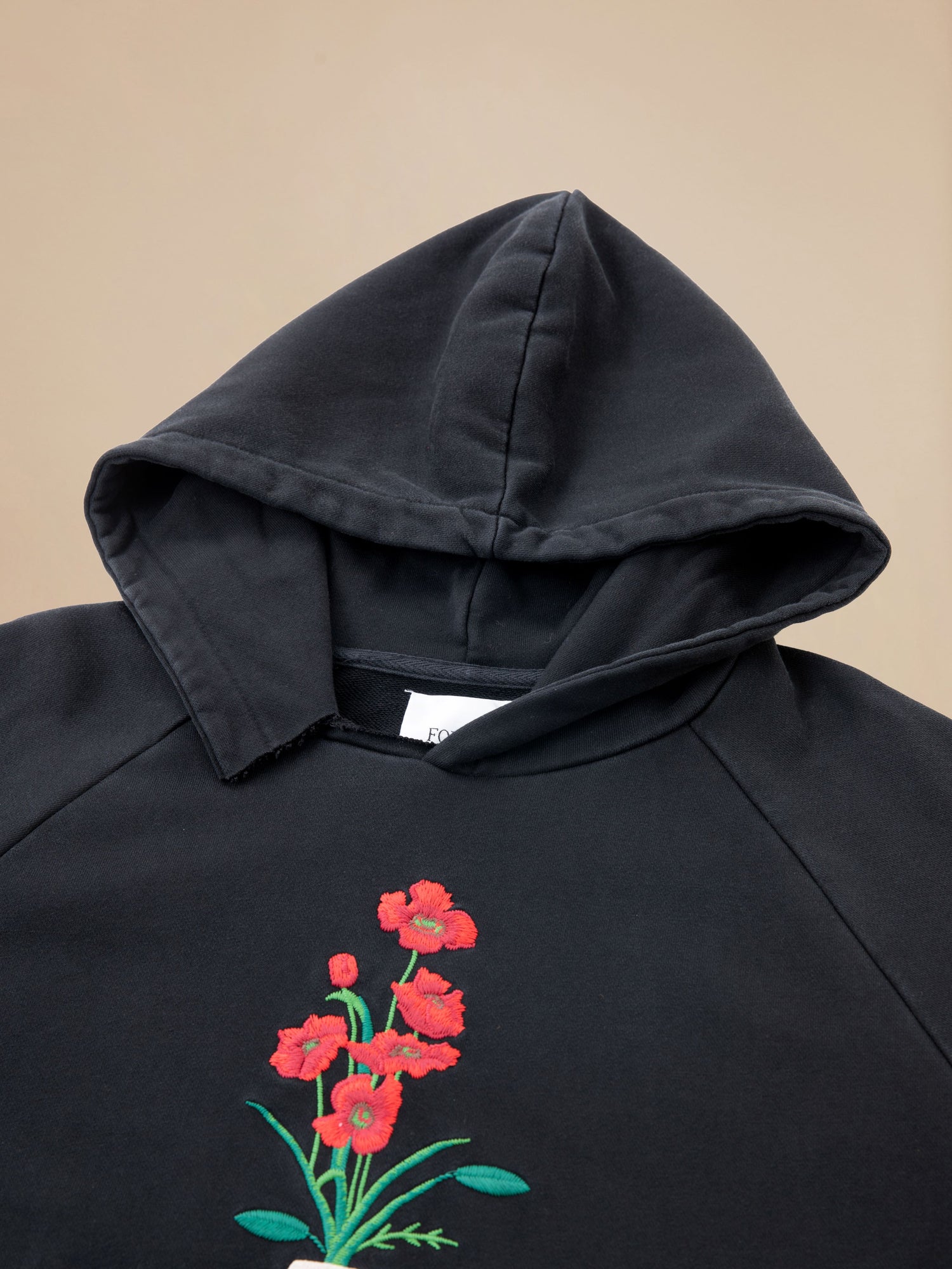 A black Flowers Vase Hoodie by Found with red flowers on it.