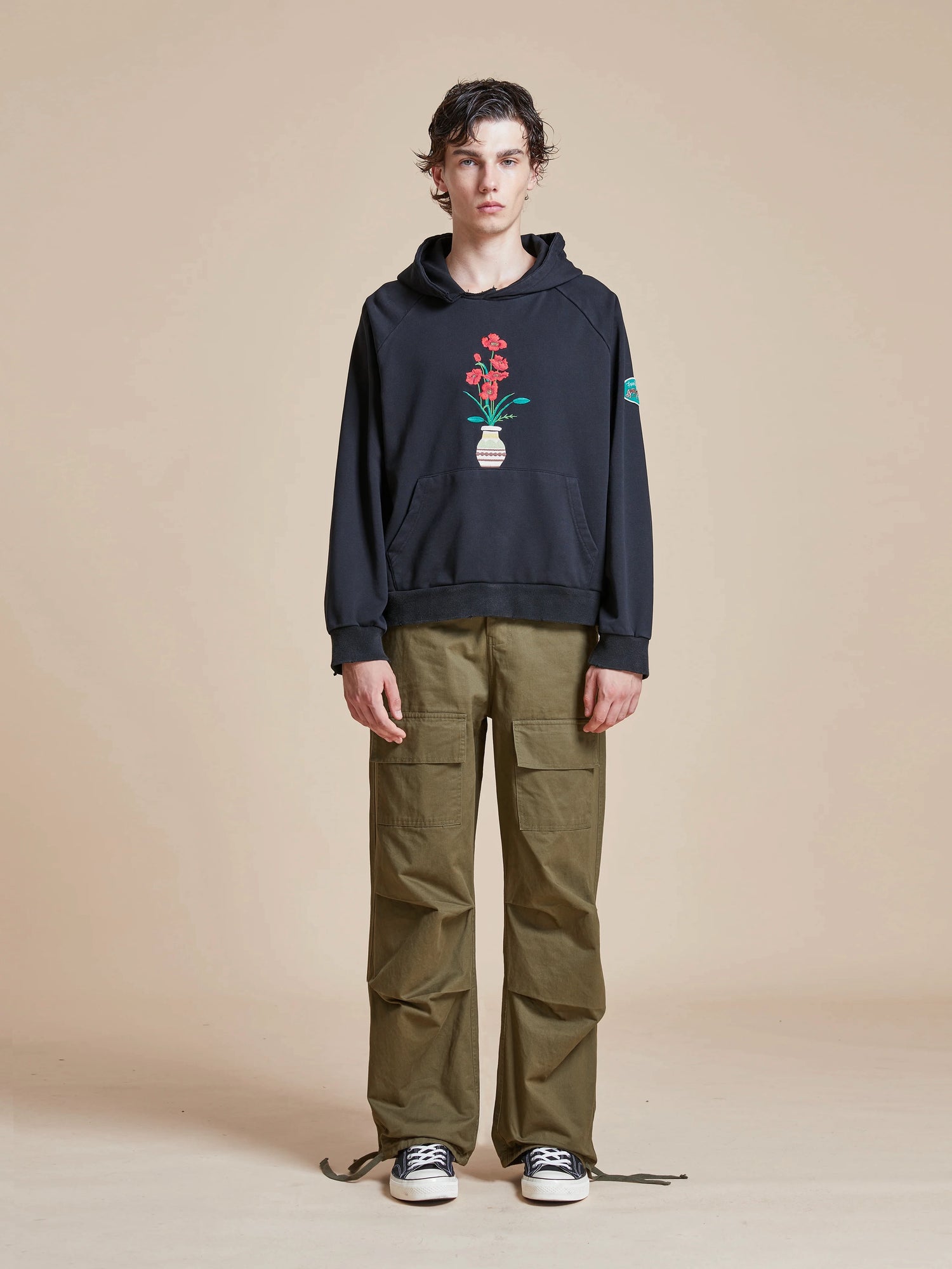 A man wearing a Flowers Vase Hoodie by Found with a vintage feel and green pants.