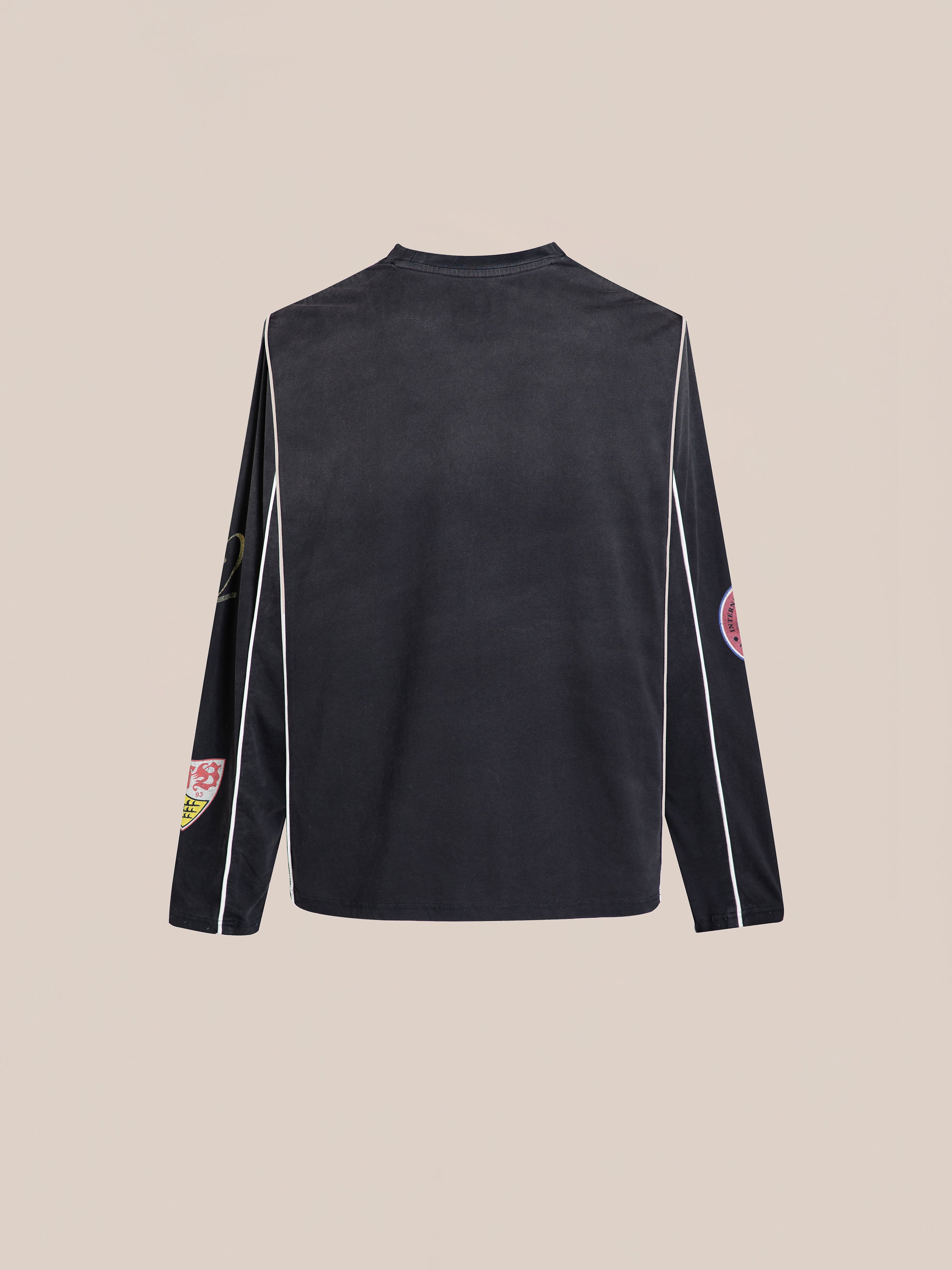 The FOUND Multi Language LS Jersey is a long-sleeve black football shirt with white piping and multicolored patches on the sleeves and shoulders, offering a retro silhouette ideal for unisex casual wear.