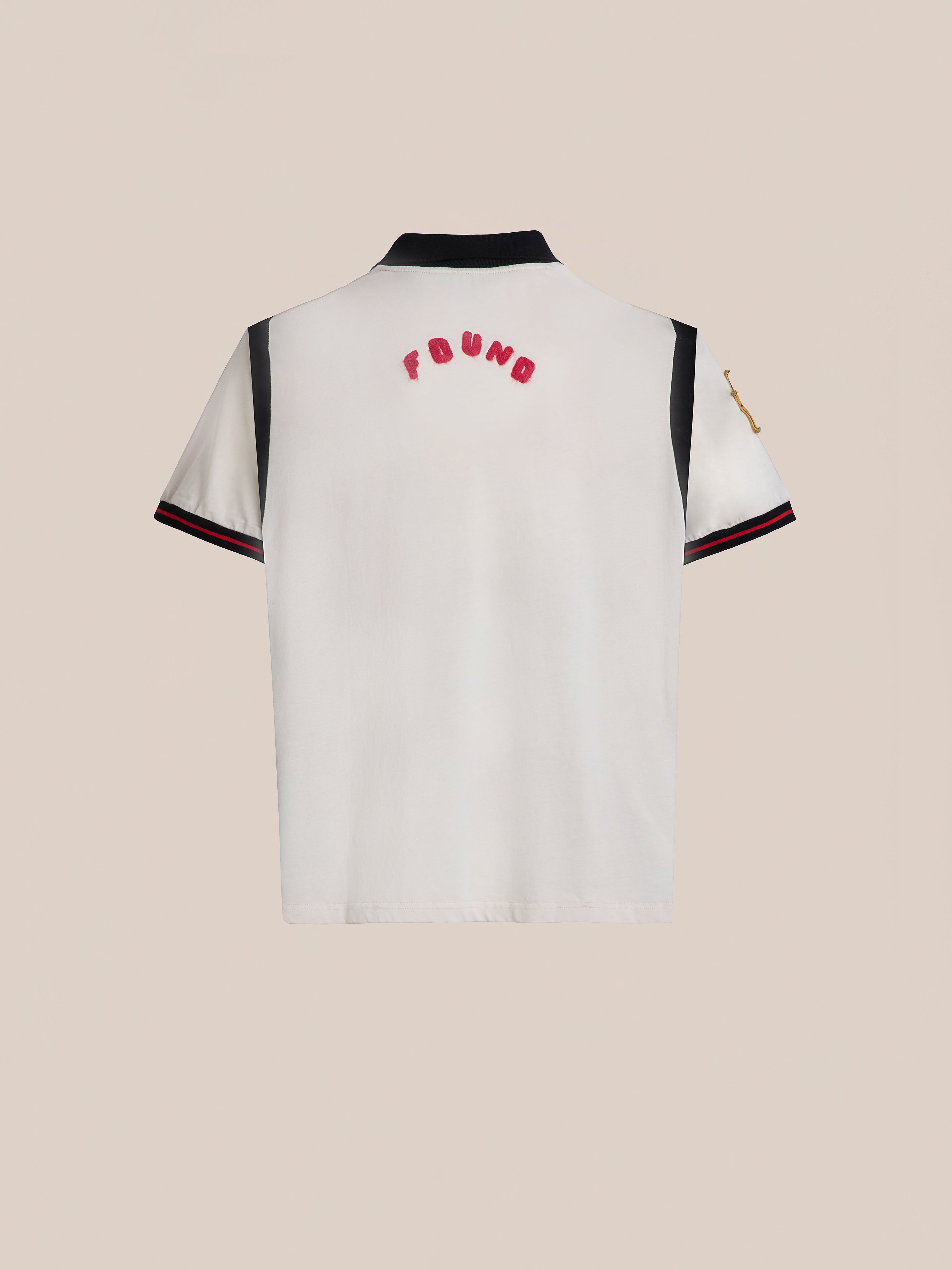 The Union Soccer Jersey by FOUND is a white short-sleeve shirt featuring black collar and sleeve details for a modern touch. "FOUND" is embroidered in bold red letters across the upper back, evoking a vintage football style.