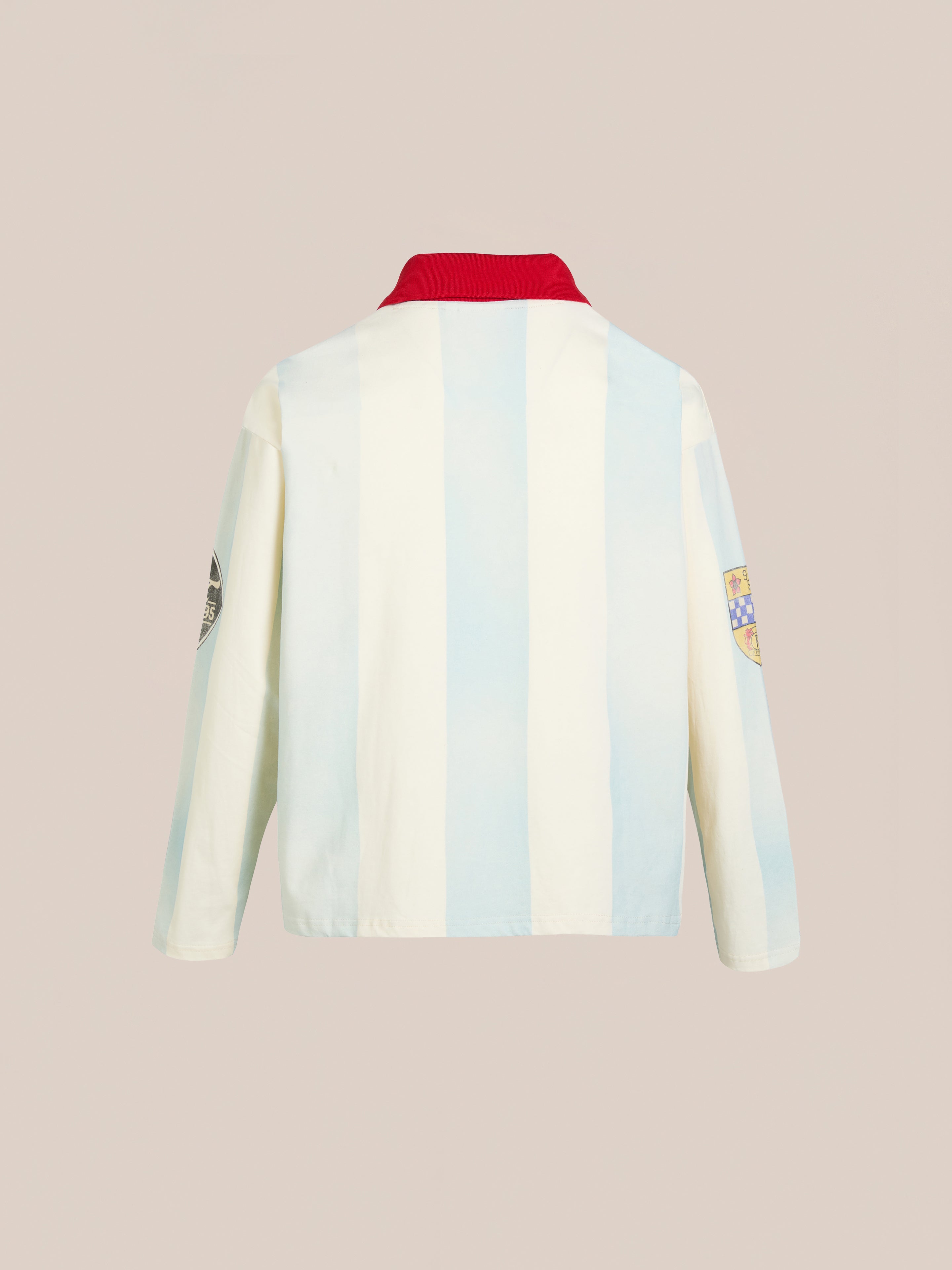 The Striped Sport LS Jersey by FOUND features a vintage sportswear-inspired design, showcasing a back view with light blue and white stripes, a red collar, and sleeve patches, all set against a plain beige background.