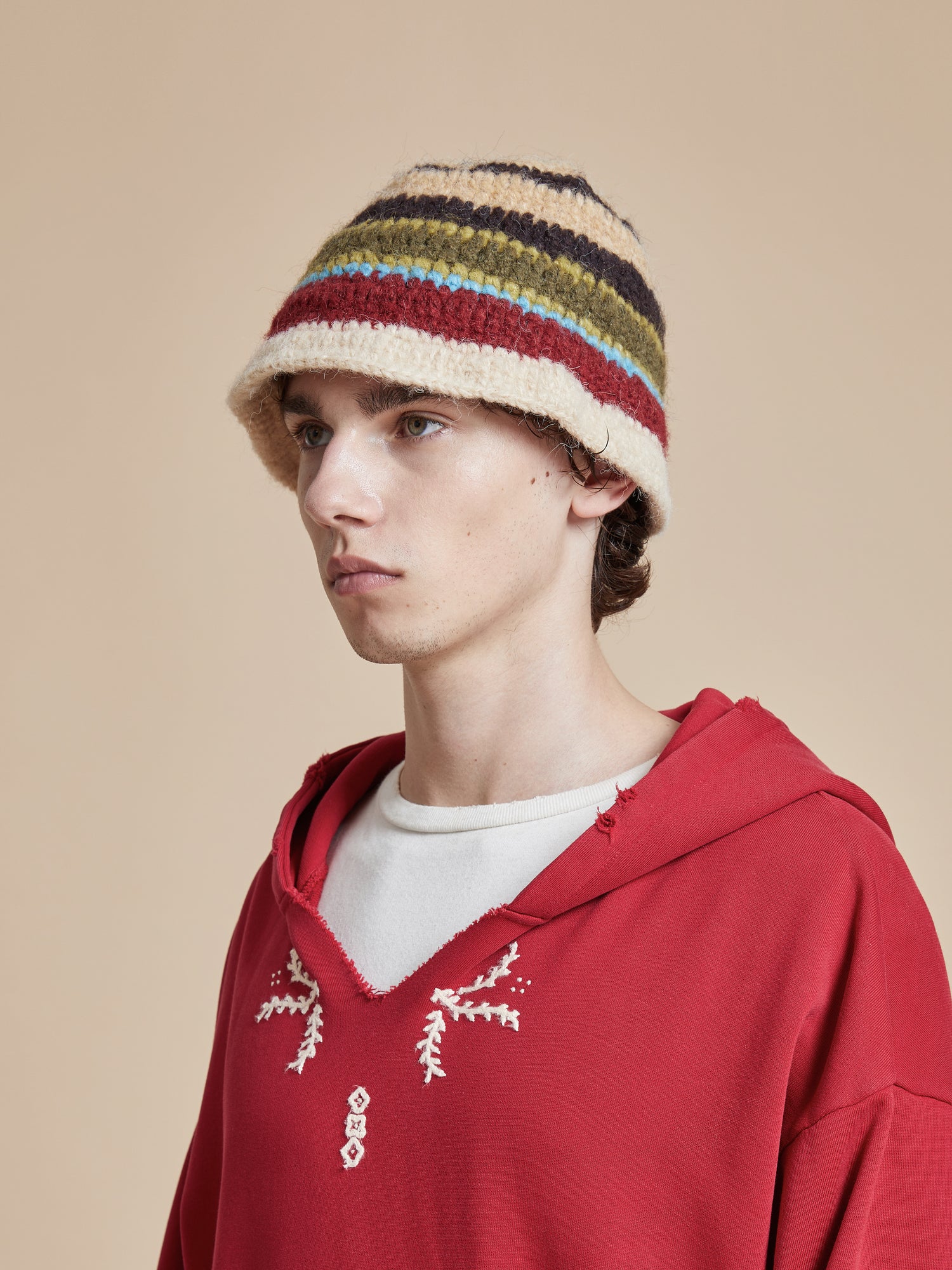 A young man wearing a red striped Found Stripe Knit Beanie hat.