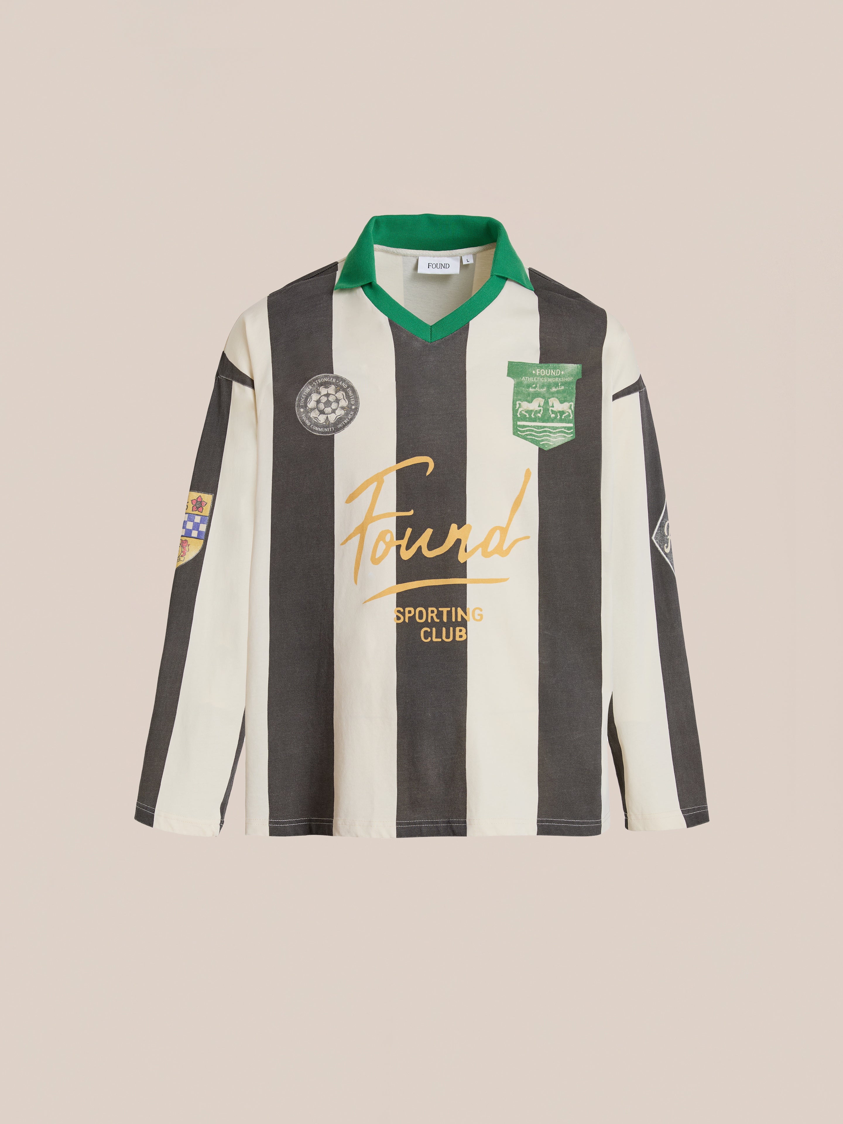 The FOUND Striped Sport LS Jersey is a unisex long-sleeve, black and white striped jersey with a relaxed fit, green collar, various patches, and "Found Sporting Club" in yellow across the front.