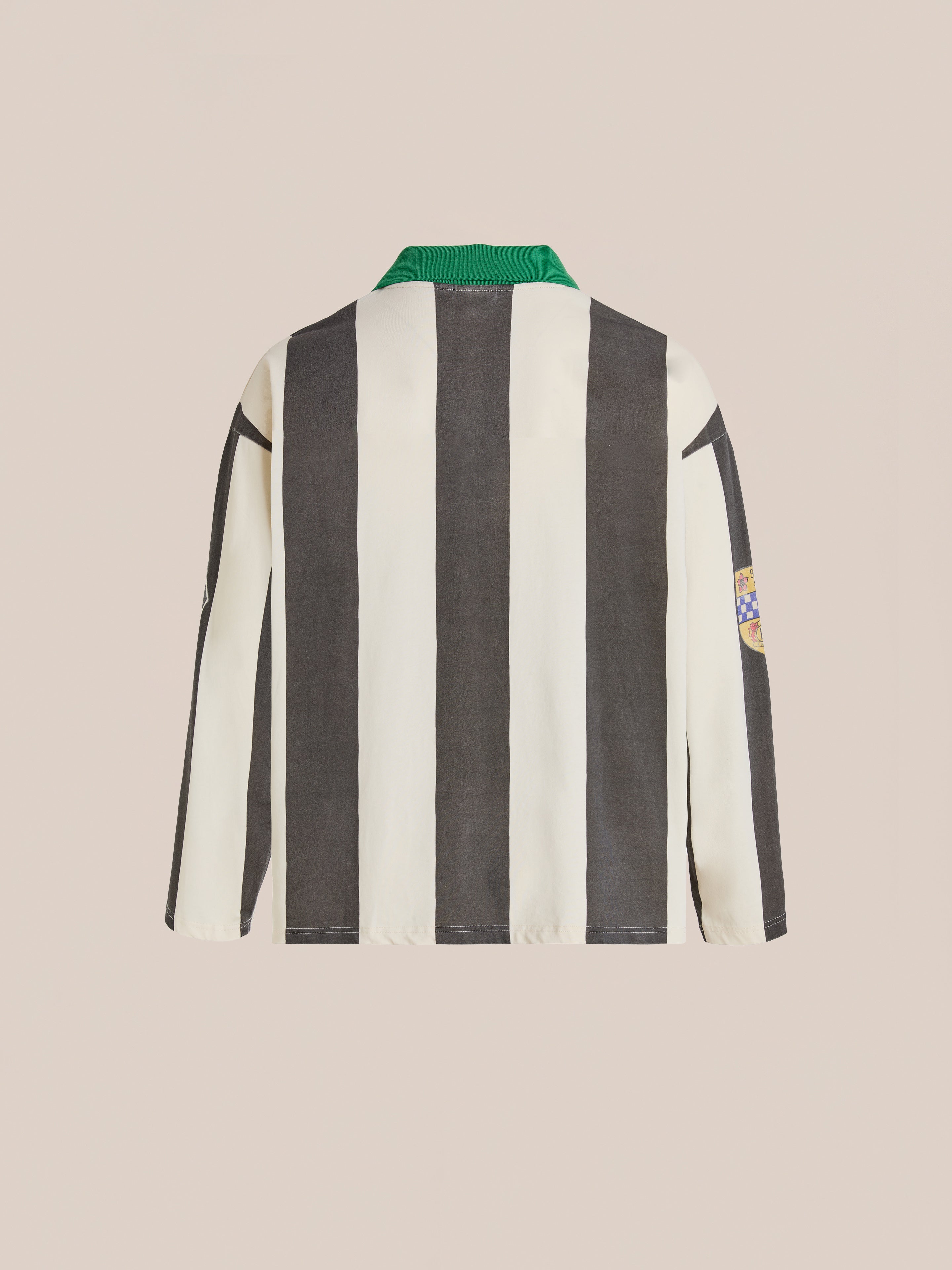 The FOUND Striped Sport LS Jersey is a relaxed fit, unisex top with black and white vertical stripes, a green collar, and a right sleeve patch, shown from the back.