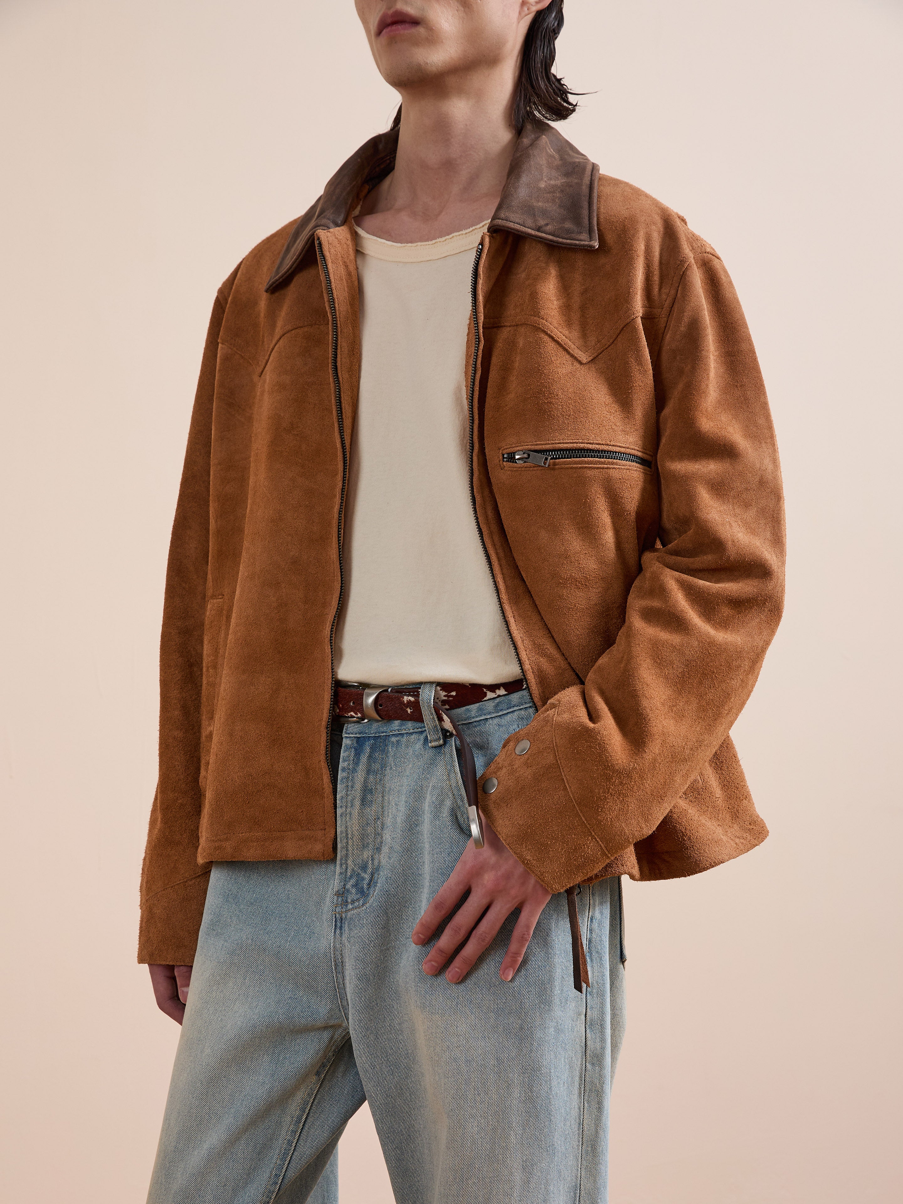 A person wearing the FOUND Suede Western Barn Jacket over a cream t-shirt and light blue jeans stands against a plain beige background.