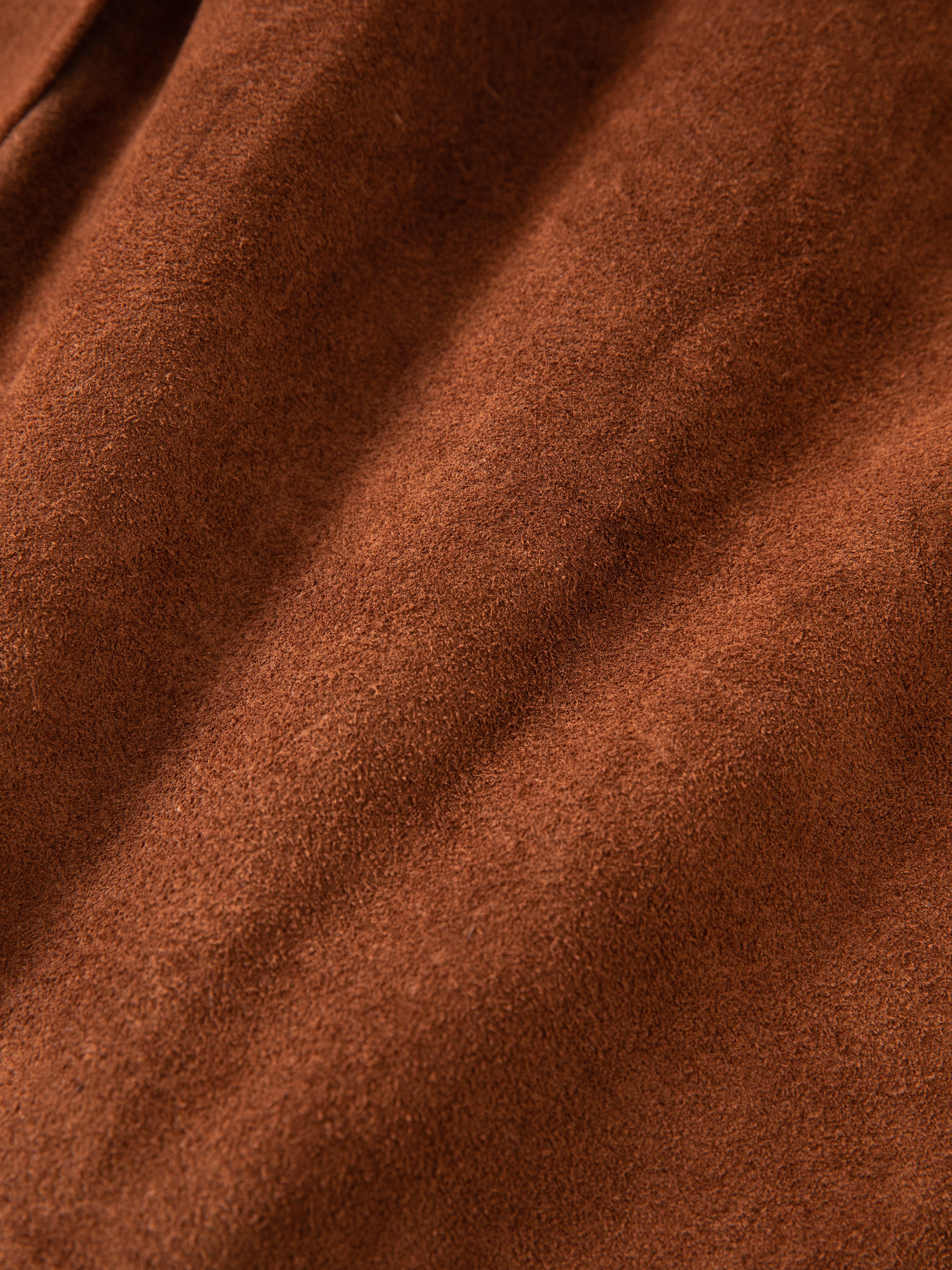 Close-up of FOUND Suede Leather Trench Coat fabric, showcasing its soft, textured brown surface with small folds and a suede-like mid-weight appearance.