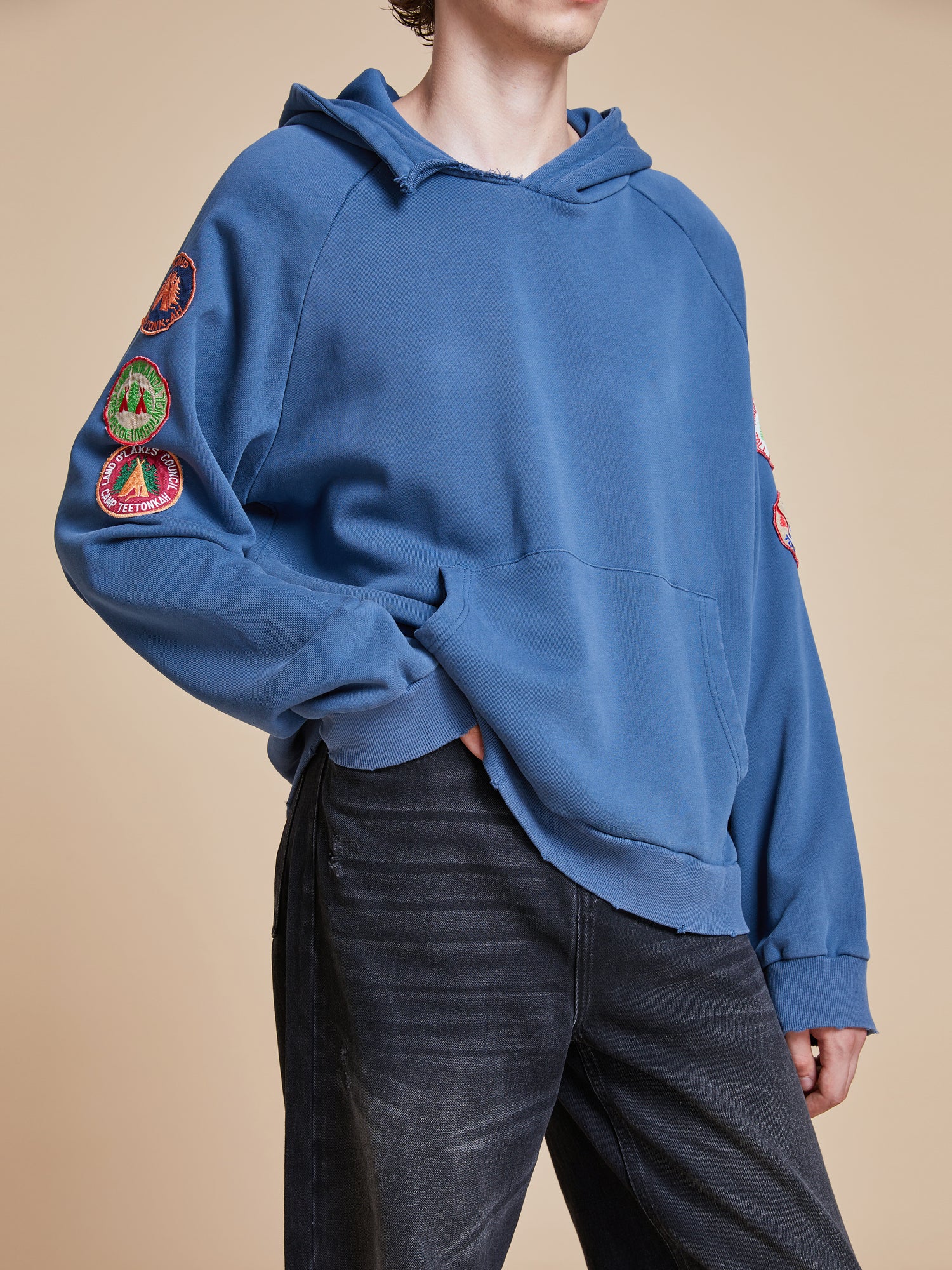 A man wearing a Timber Campground Hoodie by Found and jeans.