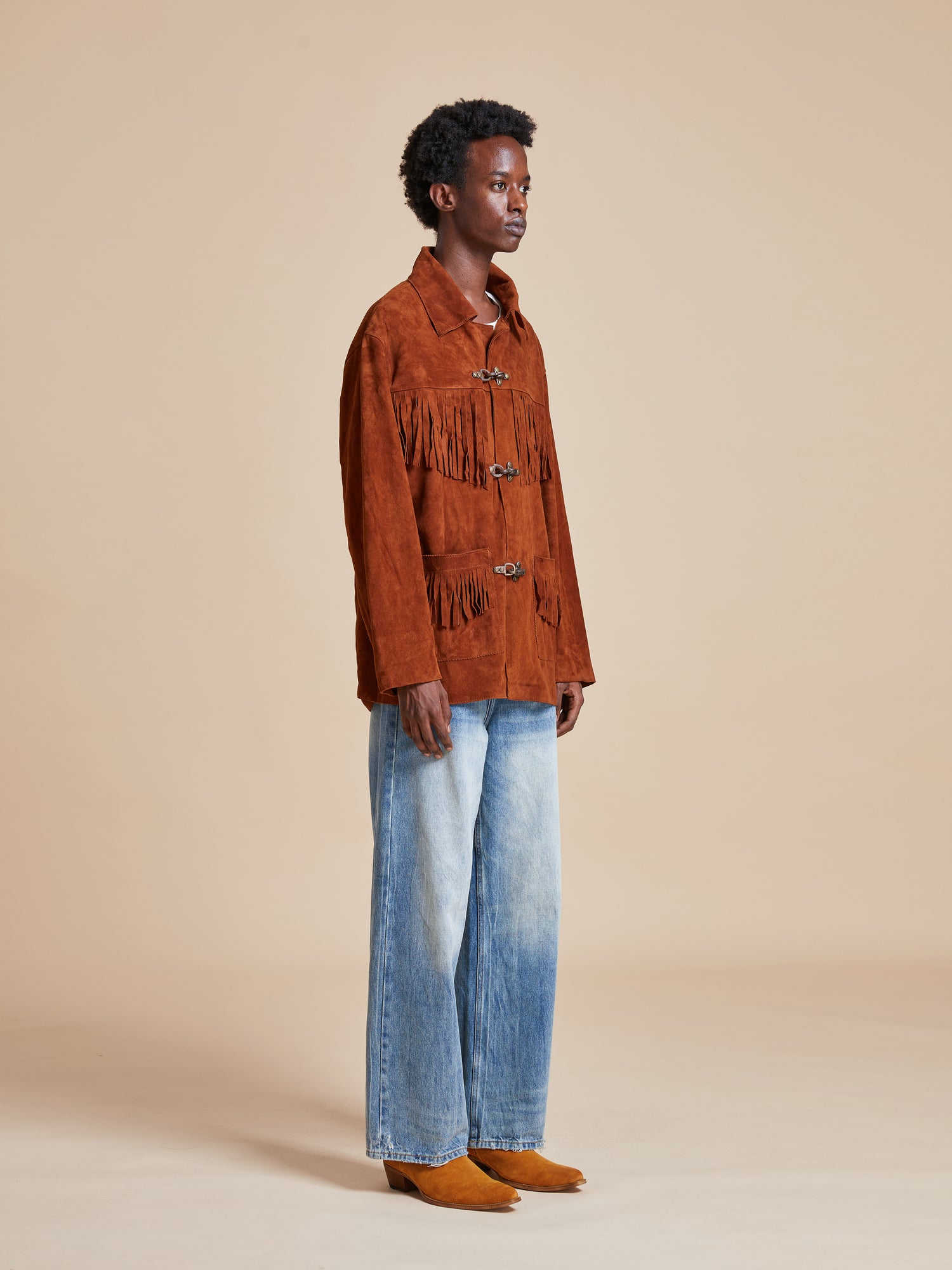 A man wearing a Found Tobacco Fringe Suede Buckle Jacket and jeans.