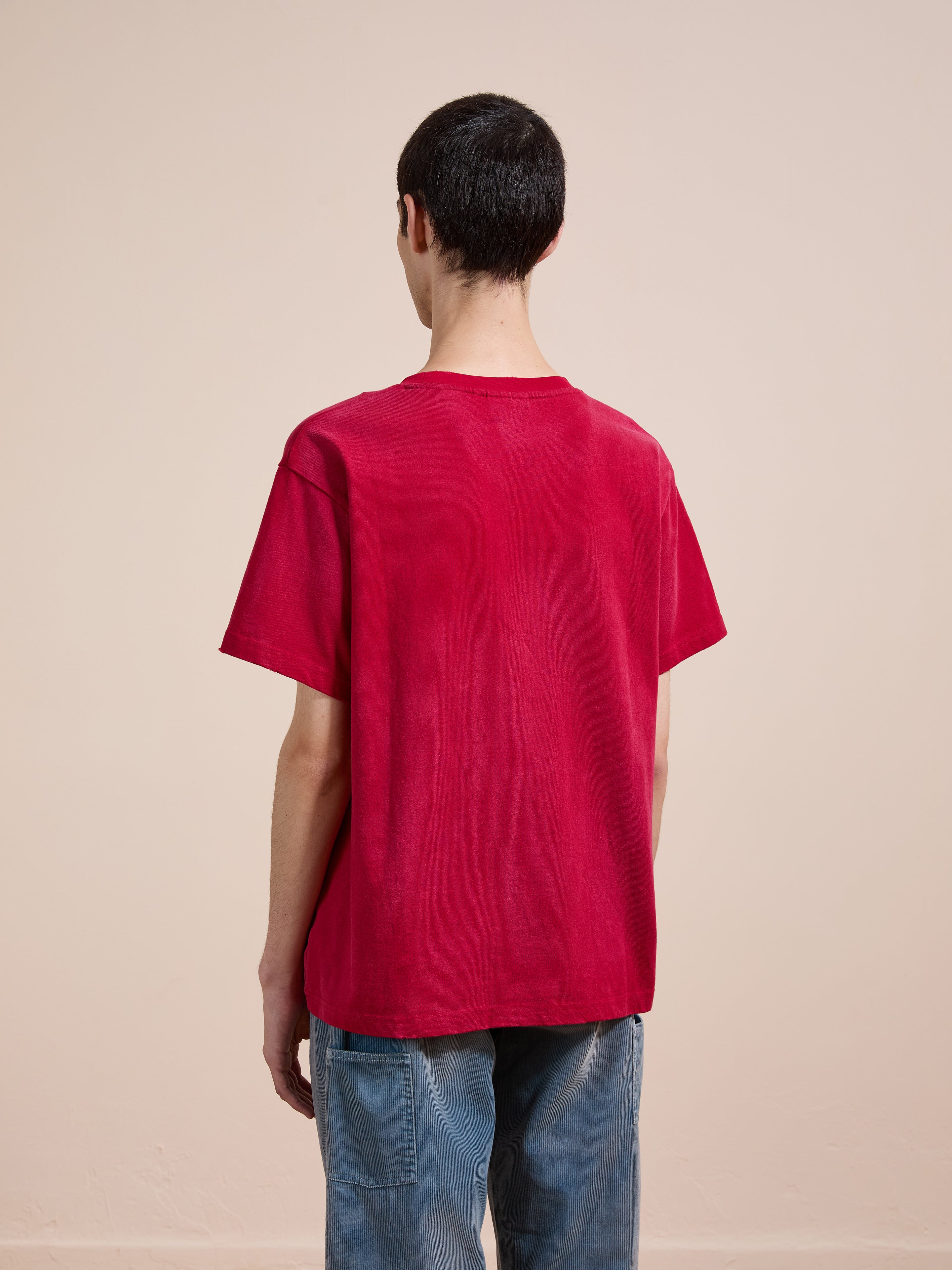 A person stands with their back to the camera, wearing the FOUND Embroidered Wildlife Tee in a unisex relaxed fit red style and blue jeans, set against a neutral background.