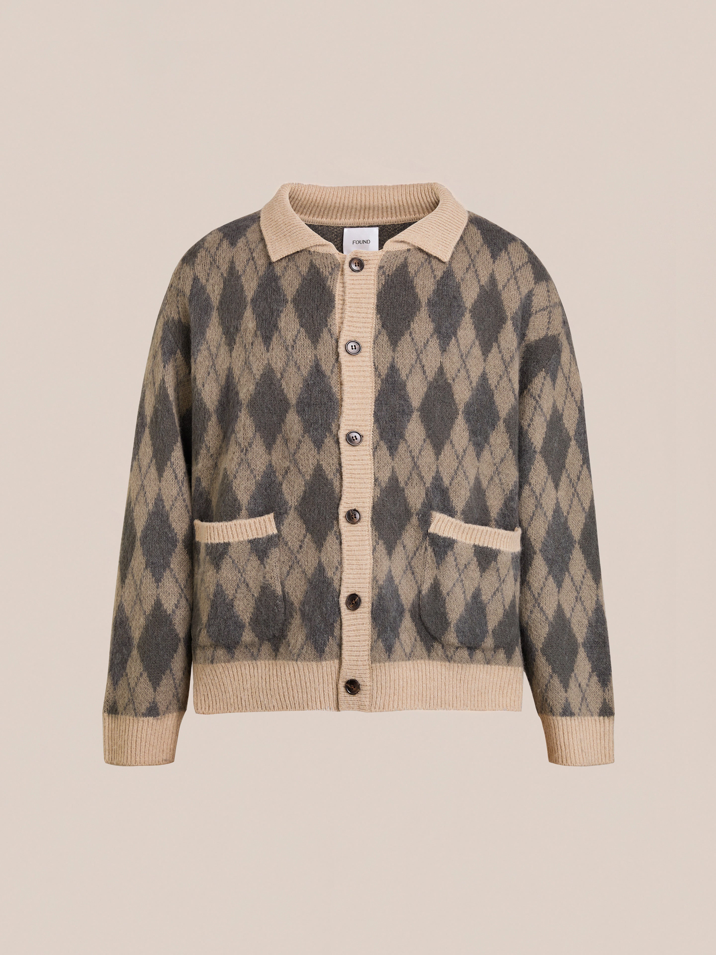 The FOUND Argyle Cardigan features a beige and gray pattern, relaxed fit, soft wool blend fabric, front buttons, two pockets, and ribbed cuffs and hem. Displayed against a plain background.