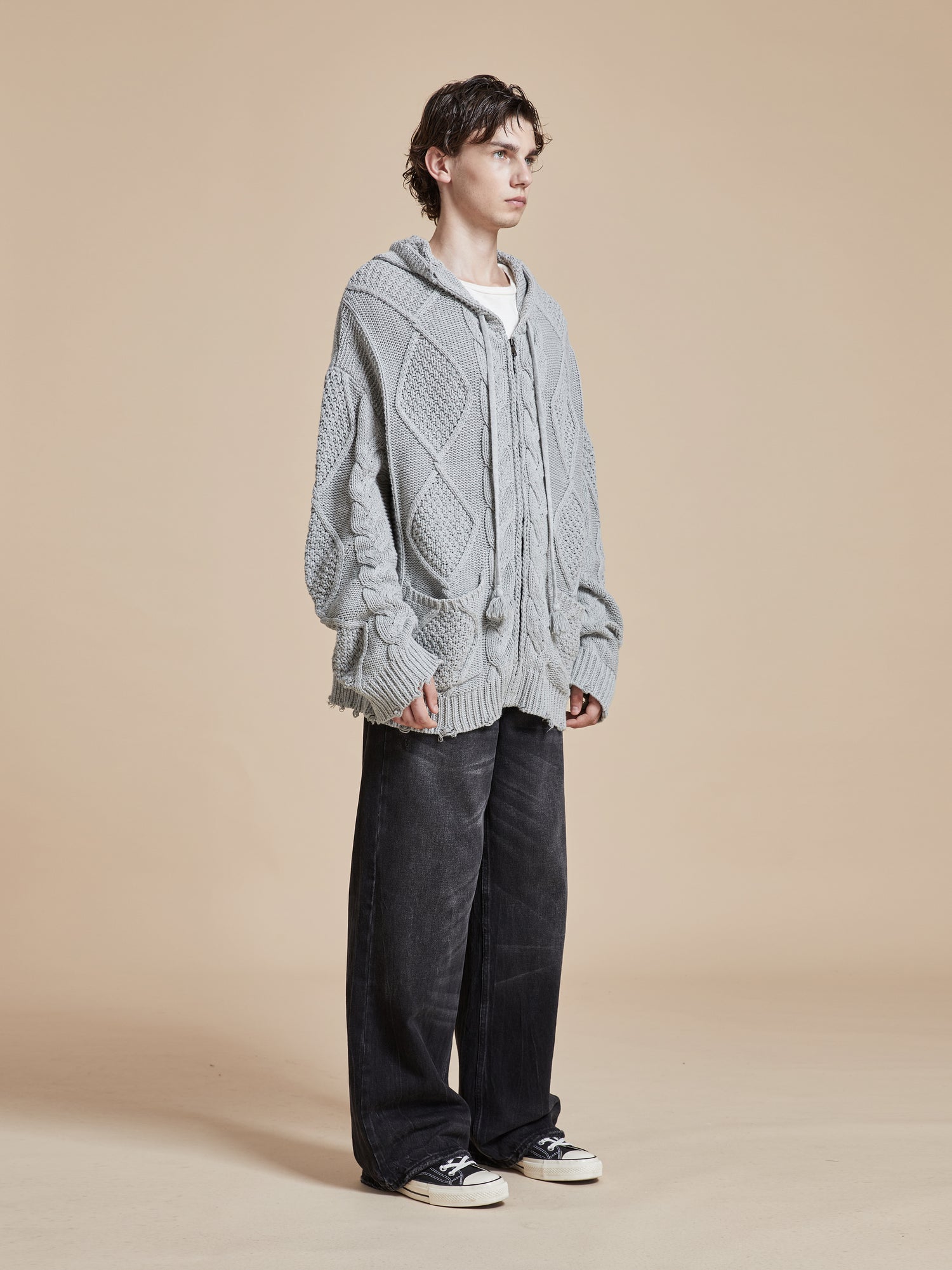The model is wearing a Zip Up Distressed Cable Knit Hoodie by Found for comfort and warmth.
